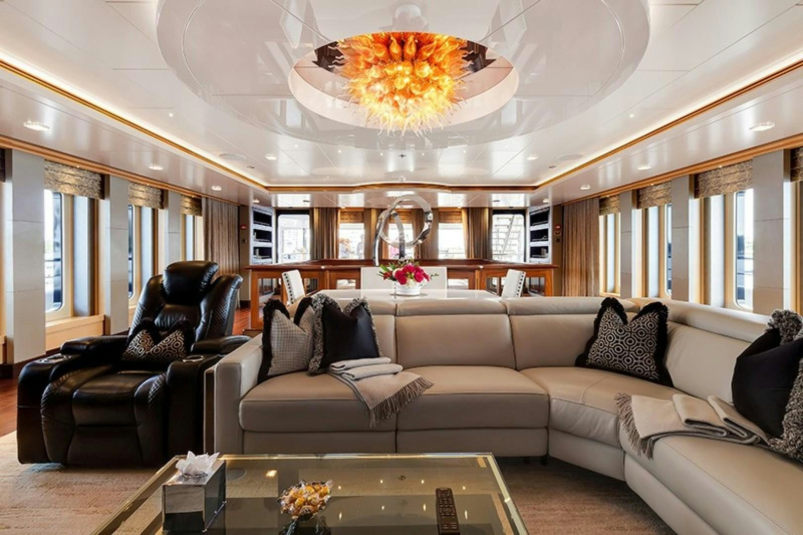 a living room with leather couches and a chandelier aboard QUANTUM OF SOLACE Yacht for Sale