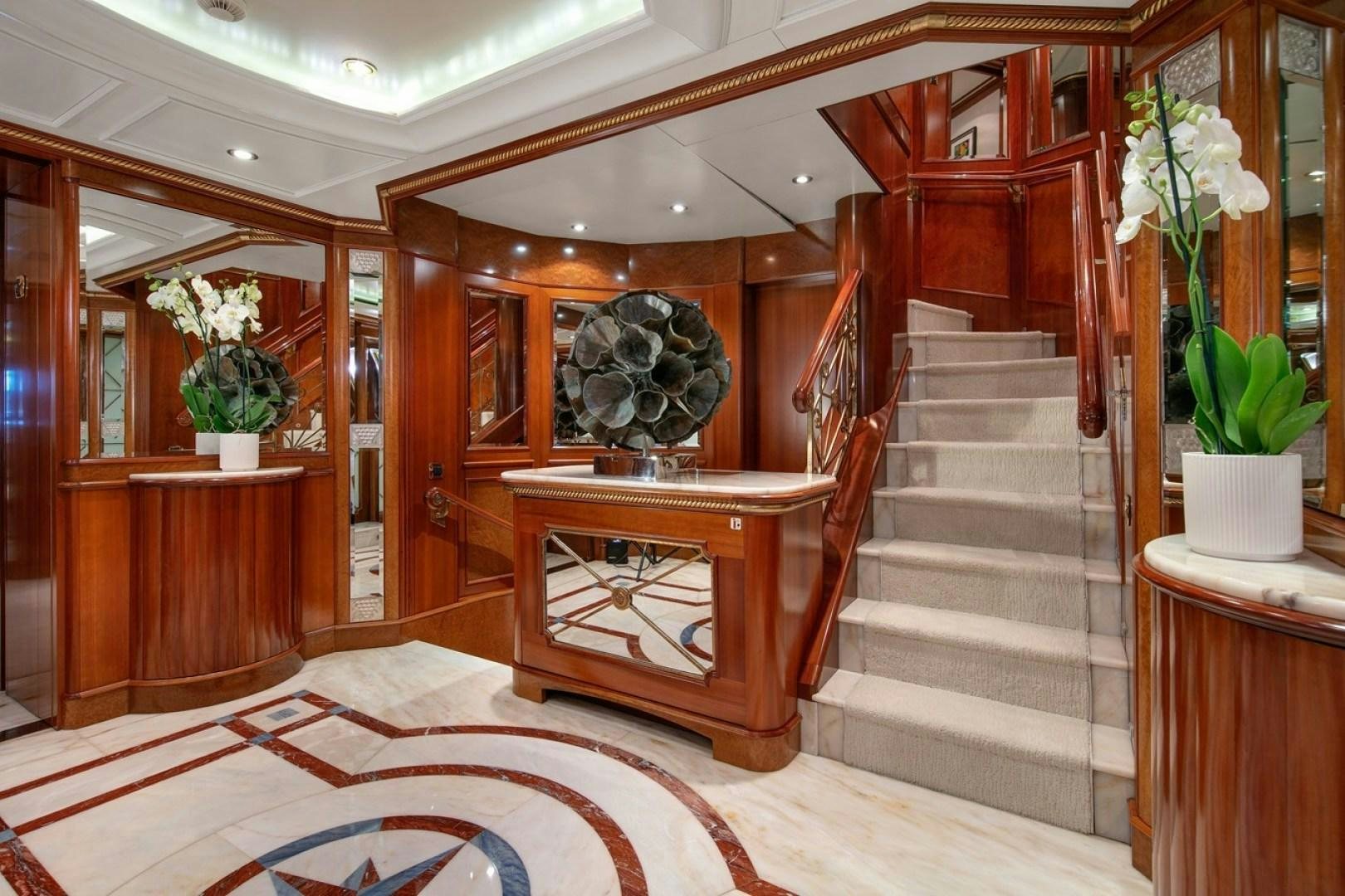 a room with a wood staircase and a large round mirror aboard NEXT CHAPTER Yacht for Sale