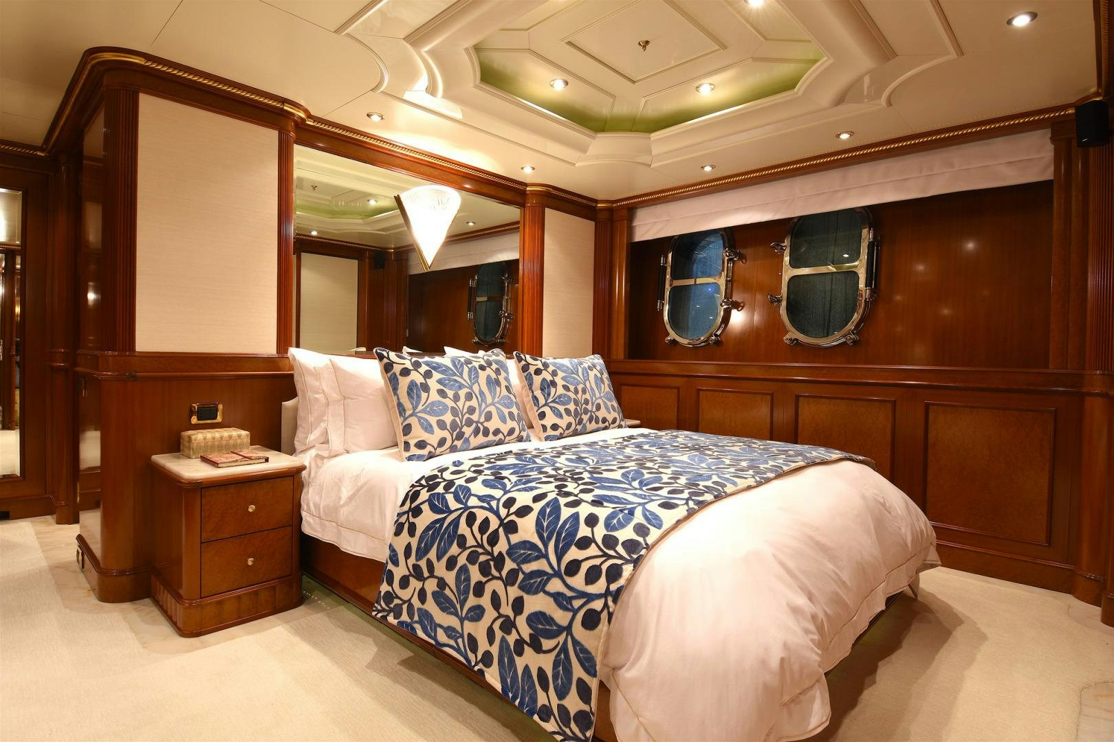 a bed with a blue and white comforter and a wooden cabinet aboard NEXT CHAPTER Yacht for Sale