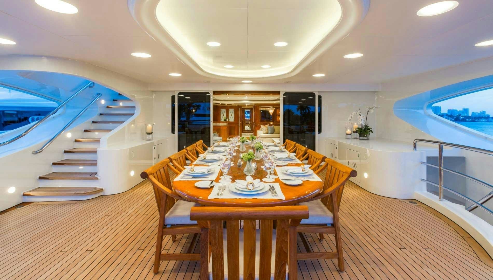 a dining table and chairs in a room with a boat in the background aboard NEXT CHAPTER Yacht for Sale