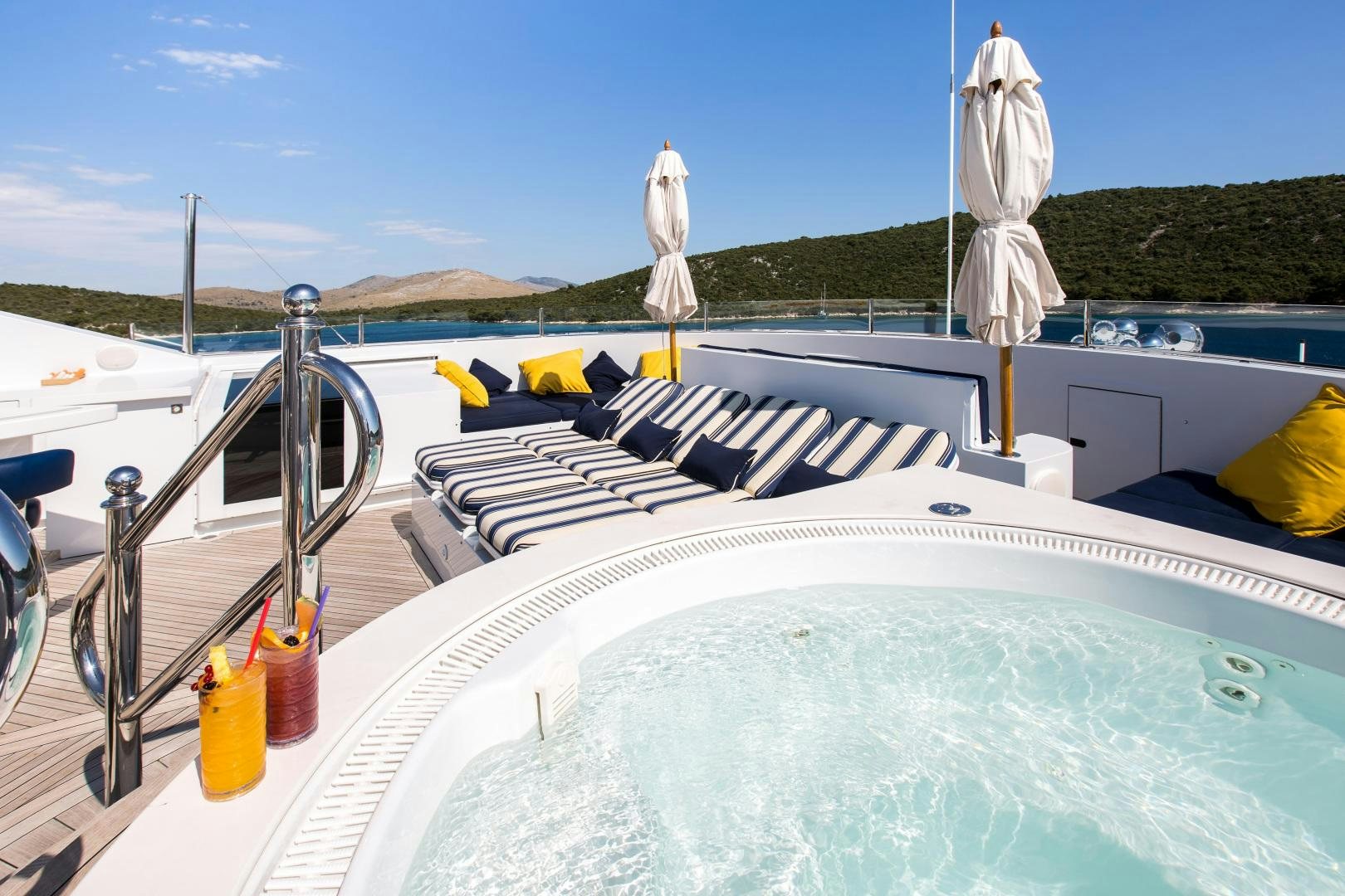 a swimming pool with a large white umbrella and a white towel from it aboard MUSTIQUE Yacht for Sale