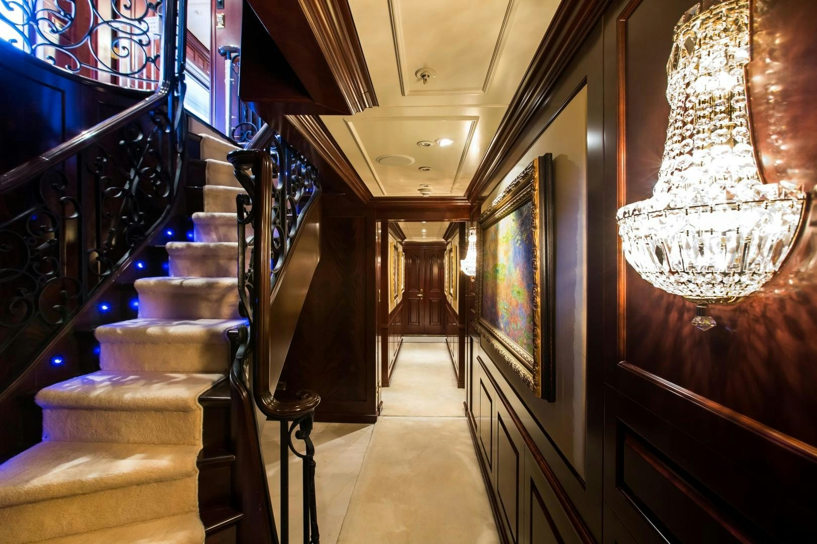 a hallway with a chandelier and a staircase aboard MUSTIQUE Yacht for Sale