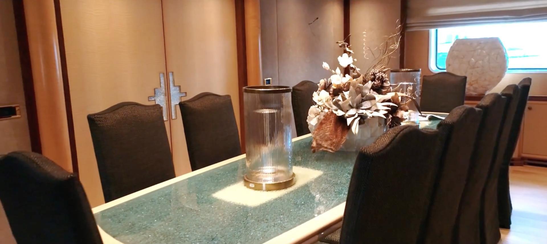 a table with chairs and a vase with flowers on it aboard ANNA J Yacht for Sale