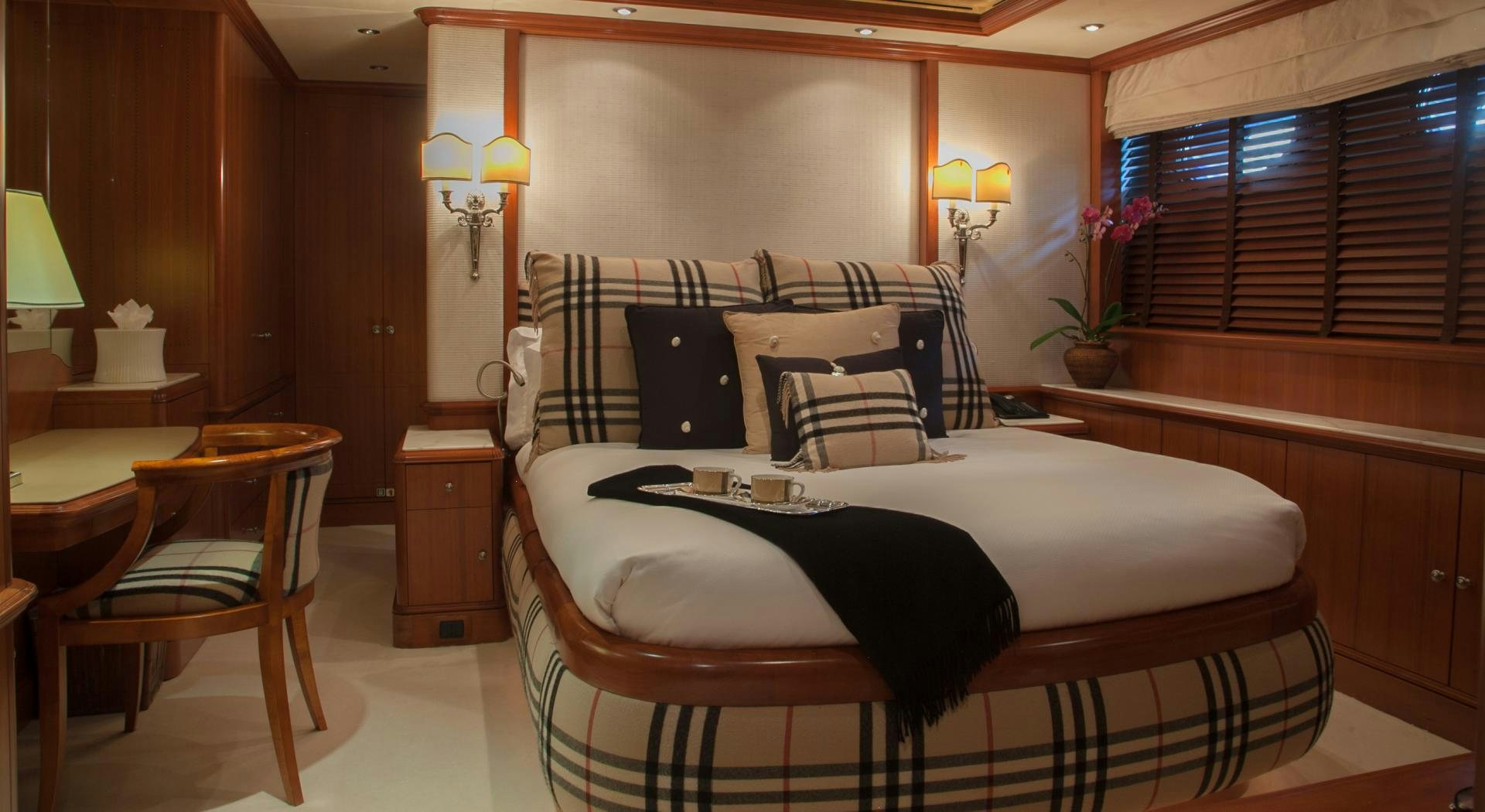 a bed with a black and white bed spread in a room with wood cabinets and a window with aboard JO I Yacht for Charter