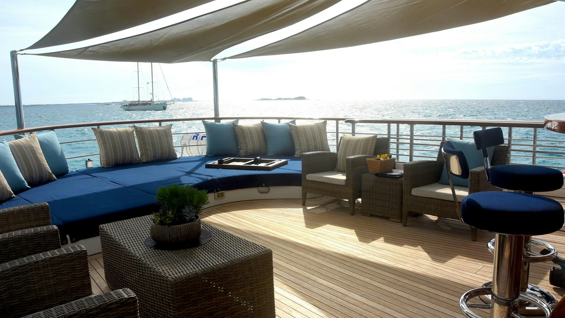 a large living room with a large blue couch and a large blue pool table with a plant on aboard OMNIA Yacht for Sale