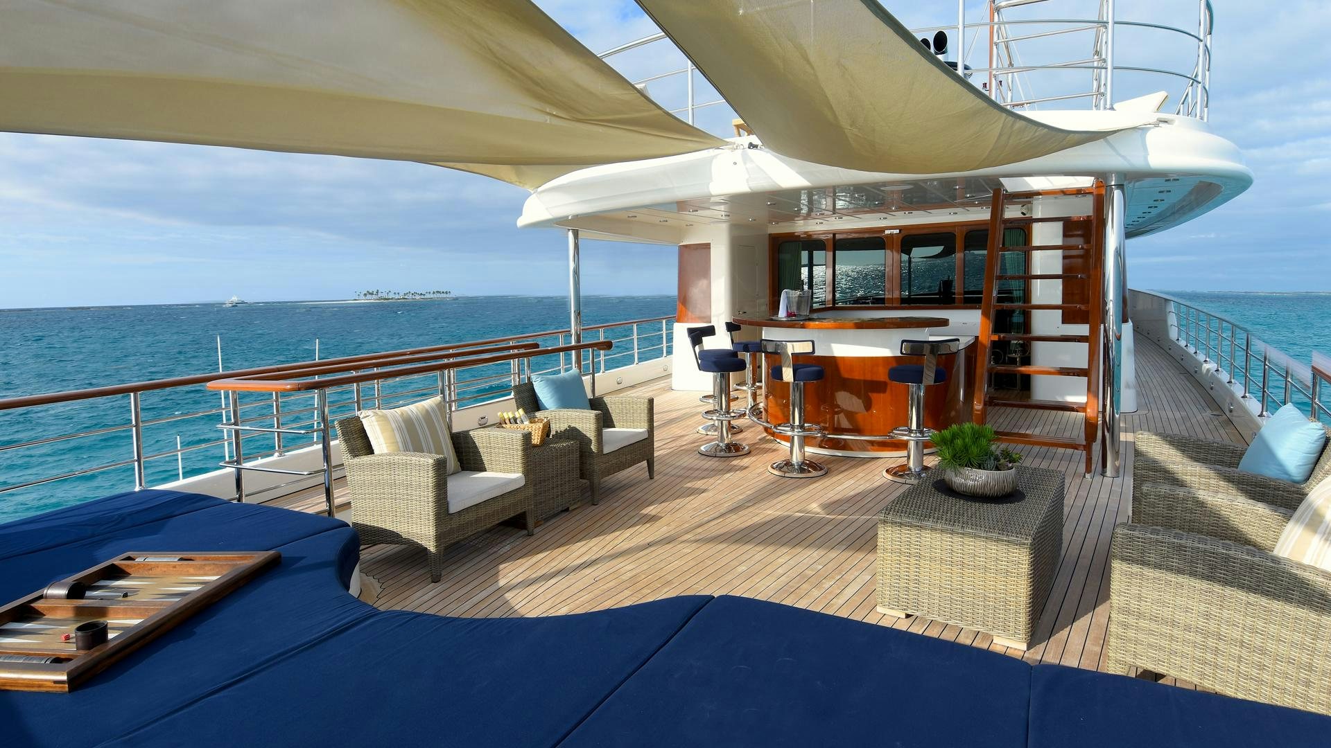 a deck with a pool and a lounge chair and a large body of water aboard OMNIA Yacht for Sale