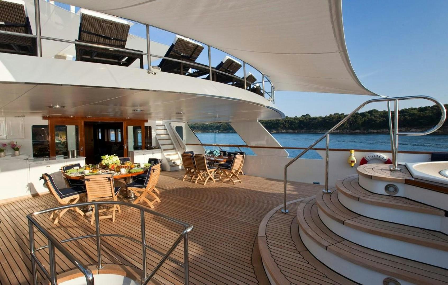 a deck with a large pool and a deck with chairs and tables aboard AUDACIA Yacht for Sale