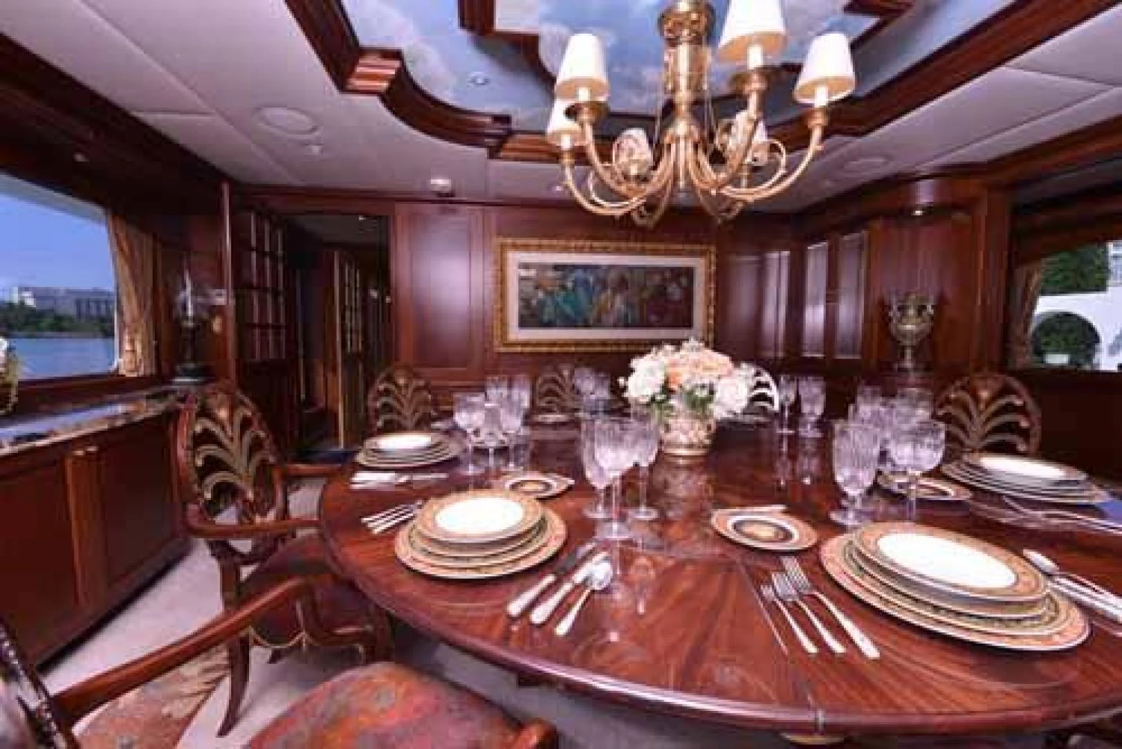 a dining room with a chandelier and a table set for a dinner aboard UTOPIA III Yacht for Sale
