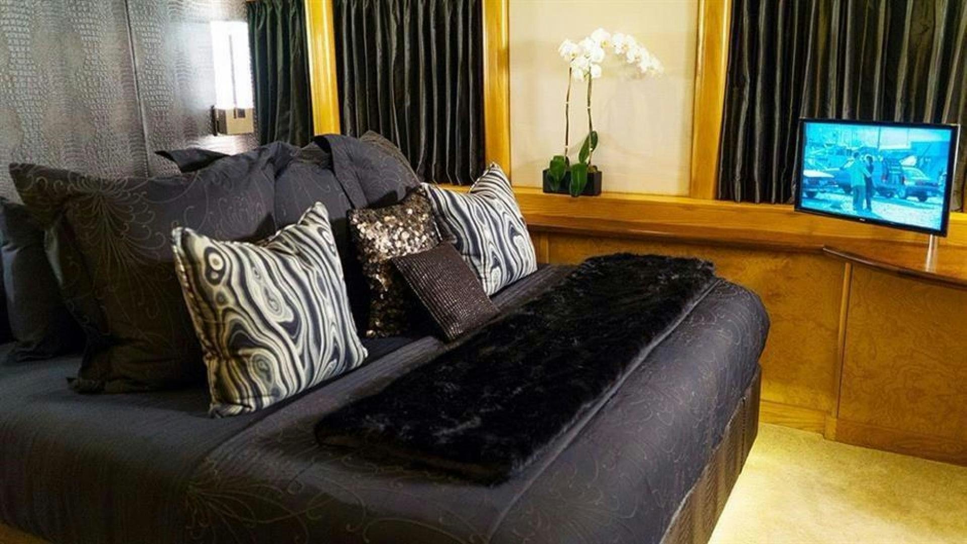 a couch with pillows and a television in the background aboard GRAND ILLUSION Yacht for Sale