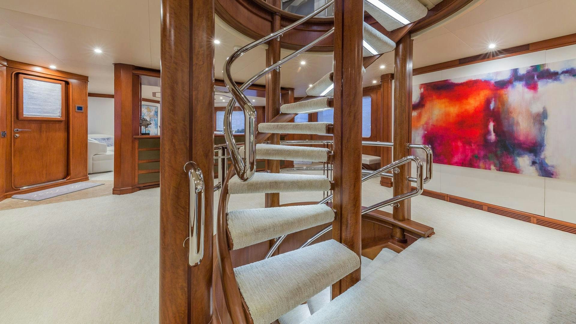a room with a staircase and paintings aboard AT LAST Yacht for Sale