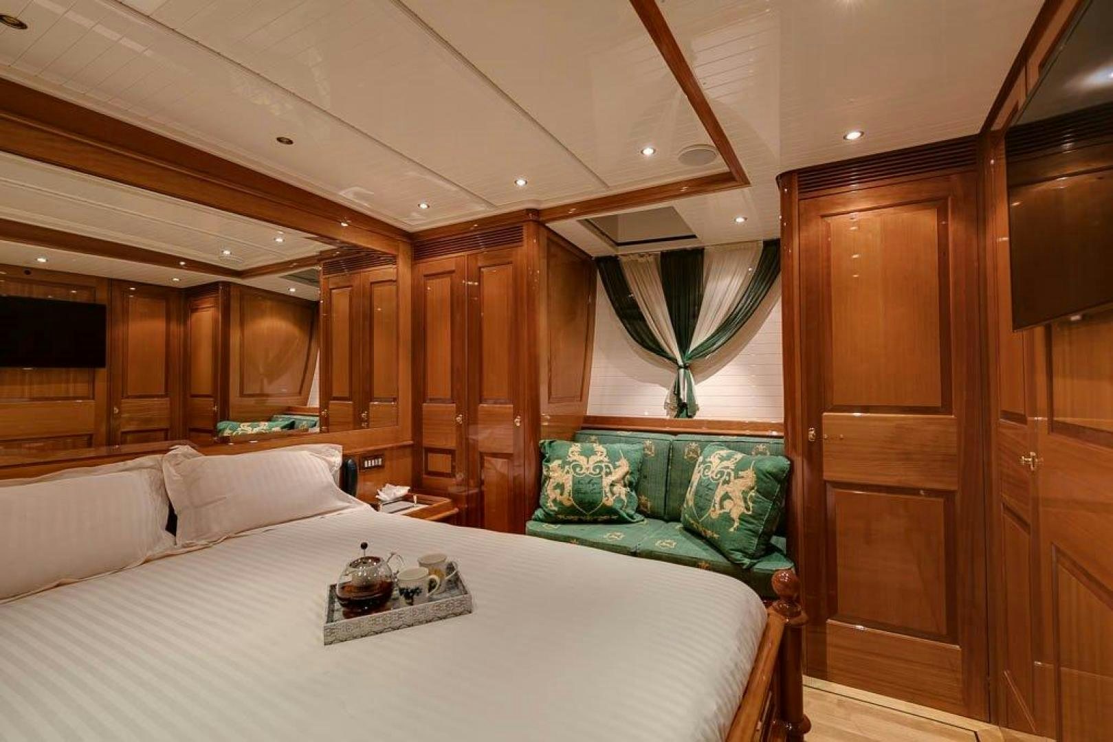 a bed with a white sheet and green pillows aboard DELUSHA Yacht for Sale