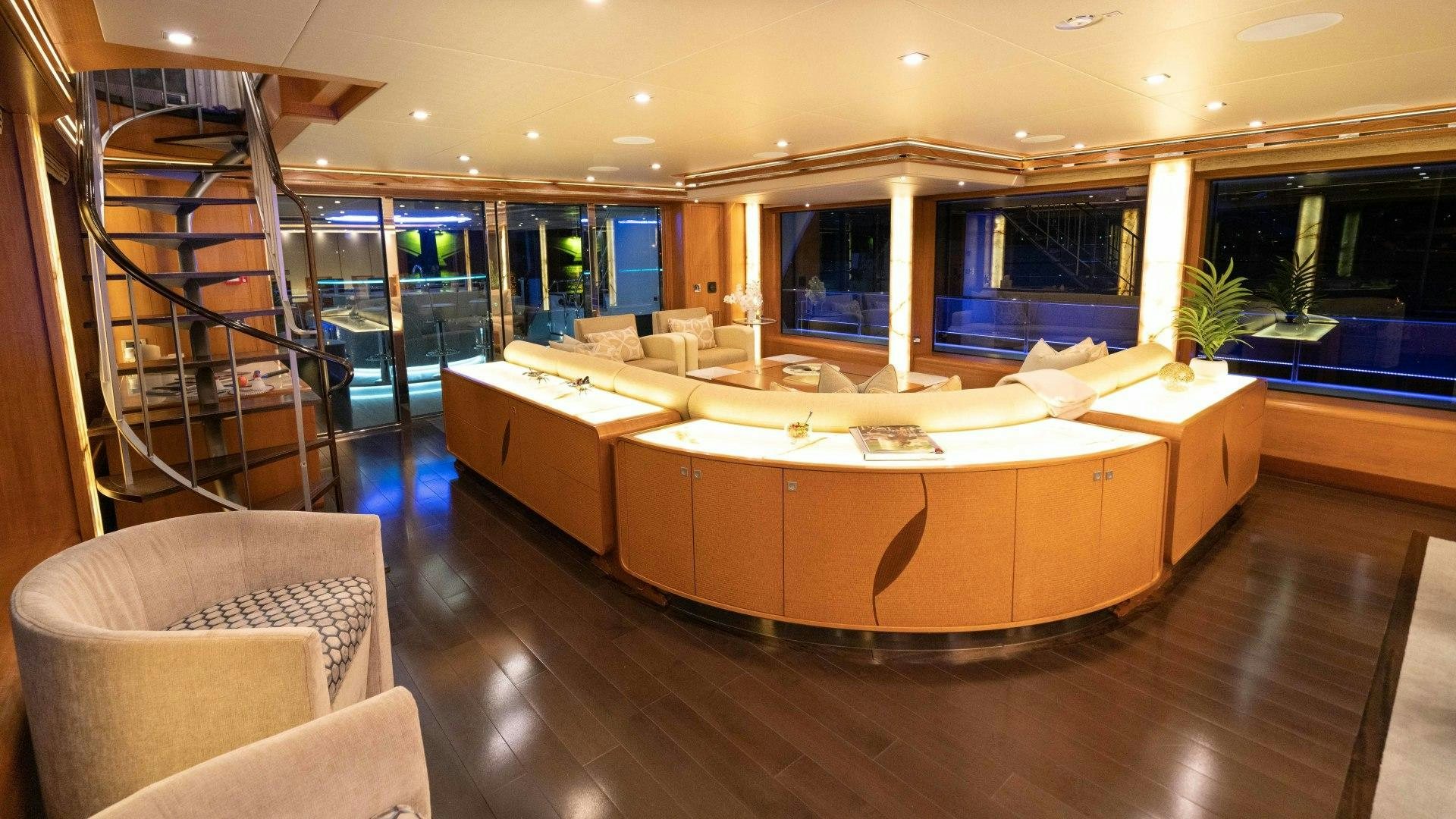 a large living room with a large couch and a staircase aboard SERENITY Yacht for Sale