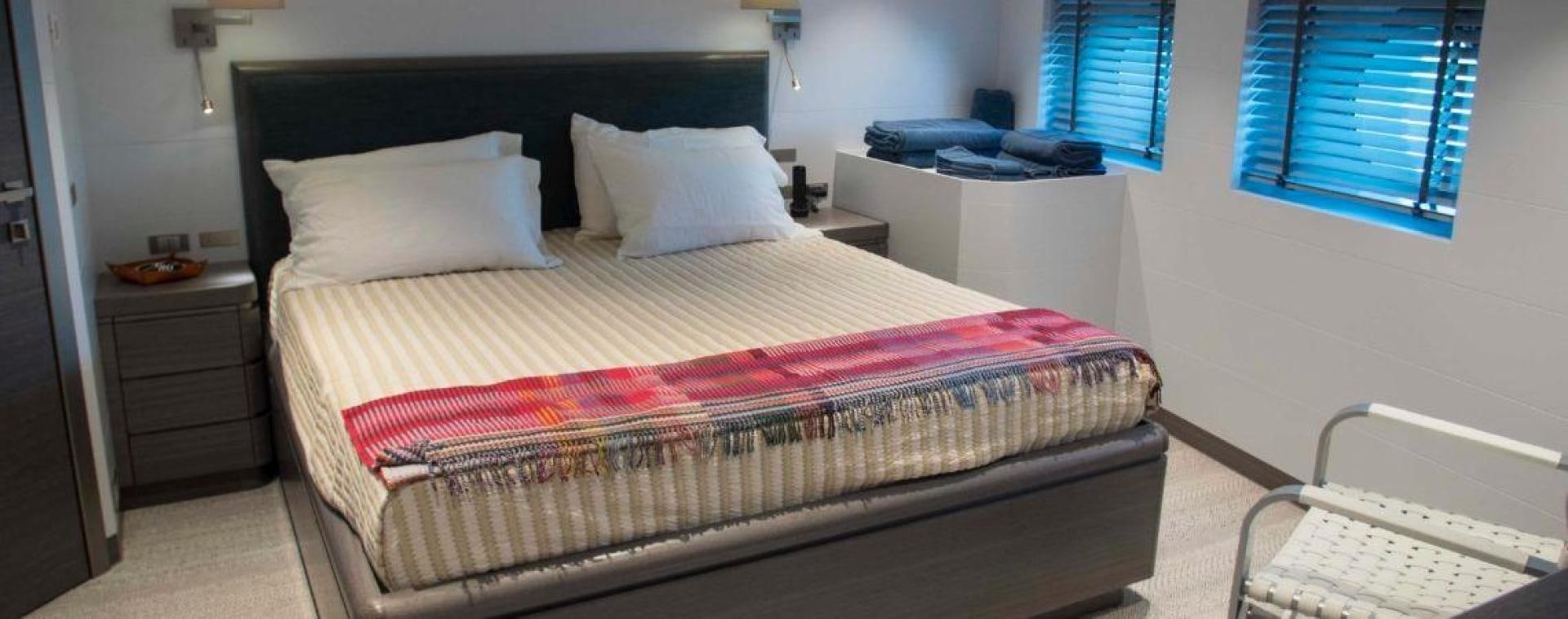 a bed with a red and white striped comforter and a white bed spread in a room with aboard NO NAME Yacht for Sale