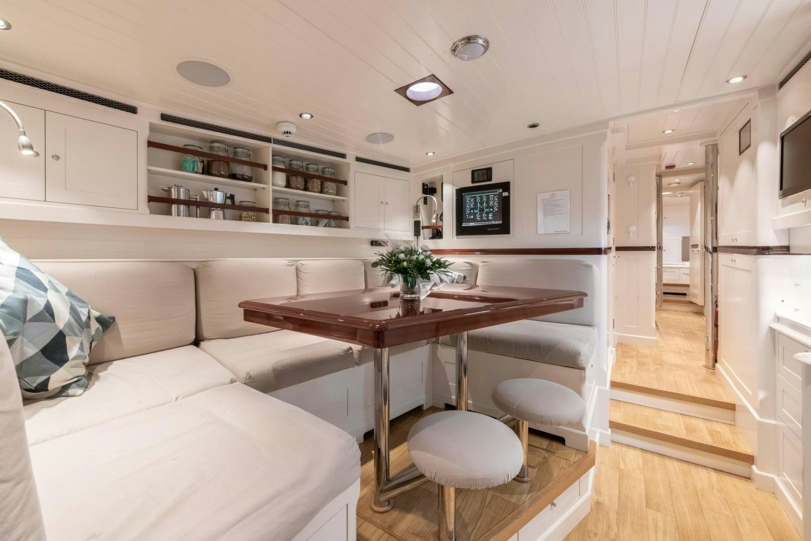a living room with a table and couches aboard RAINBOW Yacht for Sale