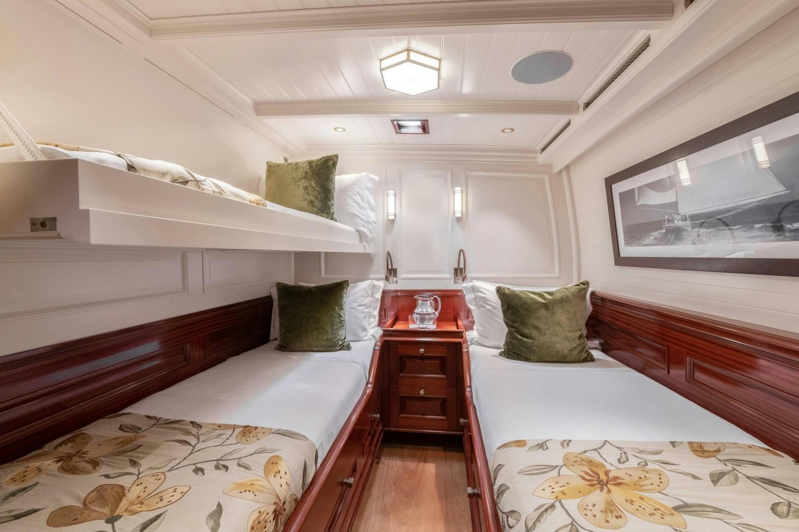a room with beds and a dresser aboard RAINBOW Yacht for Sale