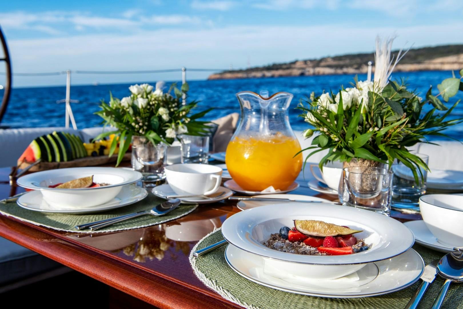 a table with plates and glasses on it with a view of the ocean aboard RAINBOW Yacht for Sale