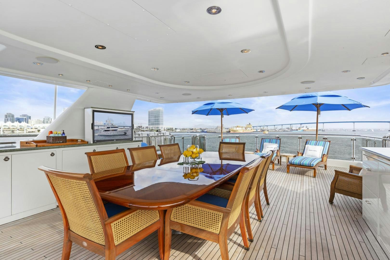 a dining table with chairs and umbrellas on a deck aboard APHRODITE Yacht for Sale