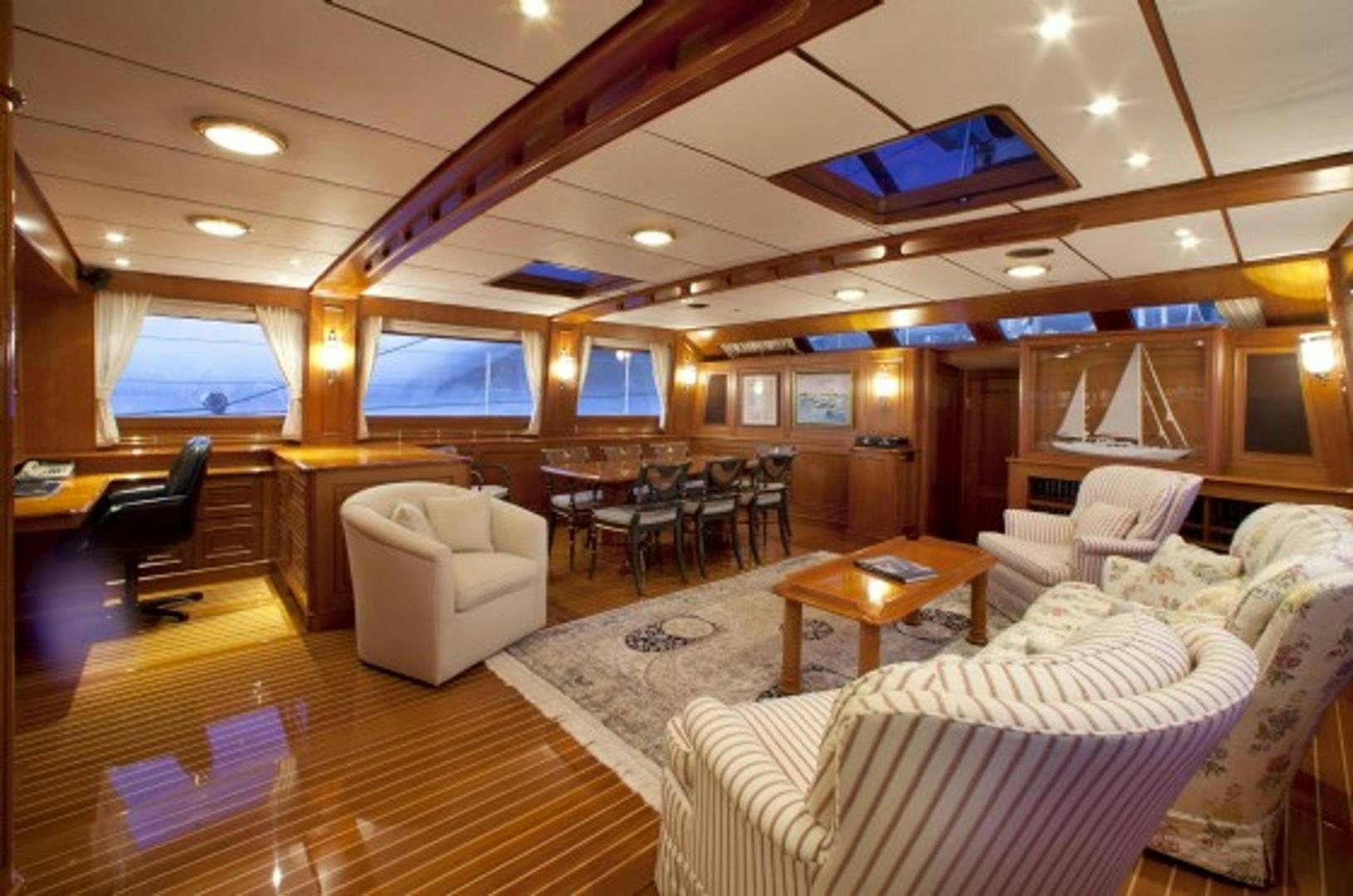 a living room with a large wood ceiling and a large wood table aboard GALILEO Yacht for Sale