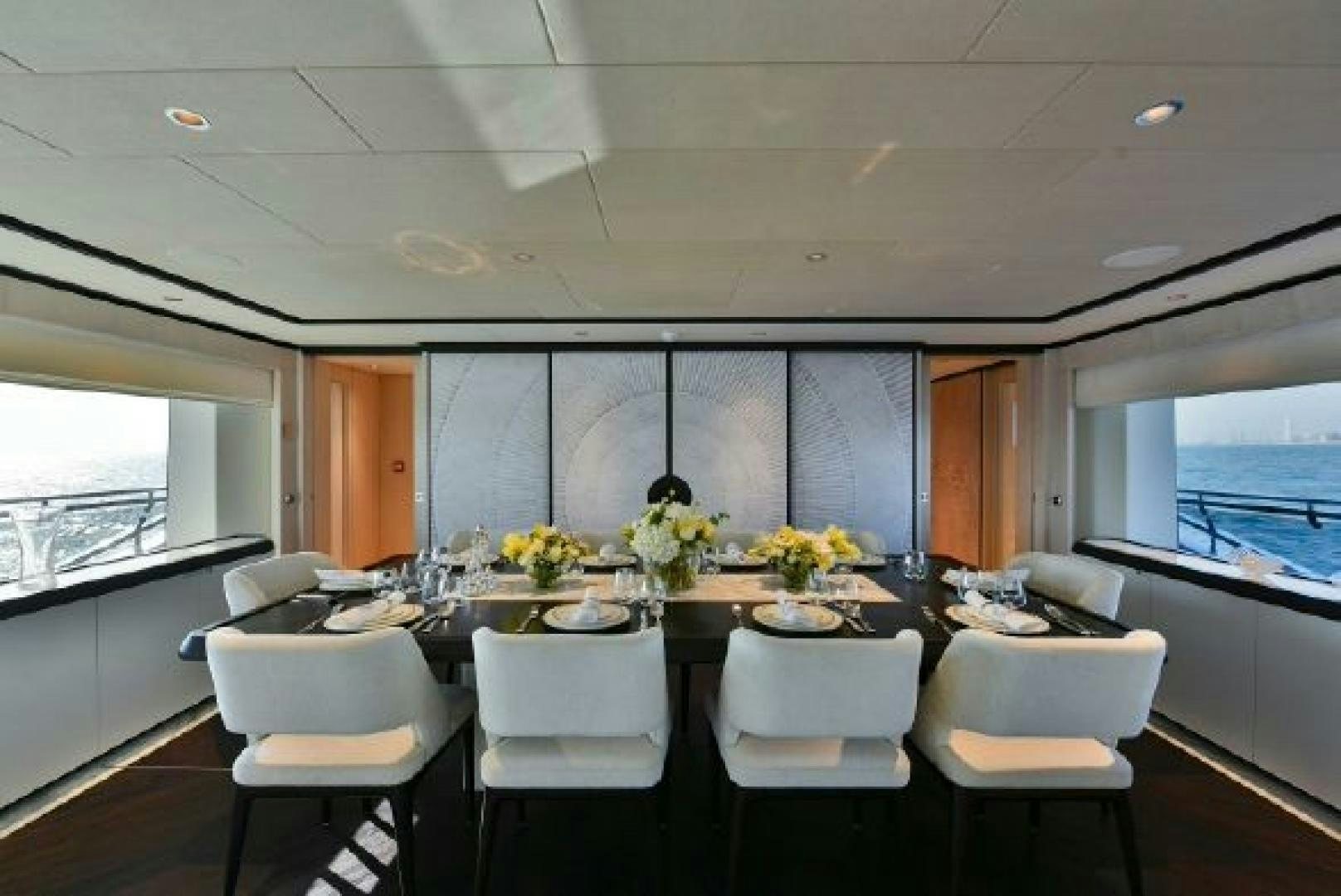 a large dining table with white chairs aboard No Name Yacht for Sale