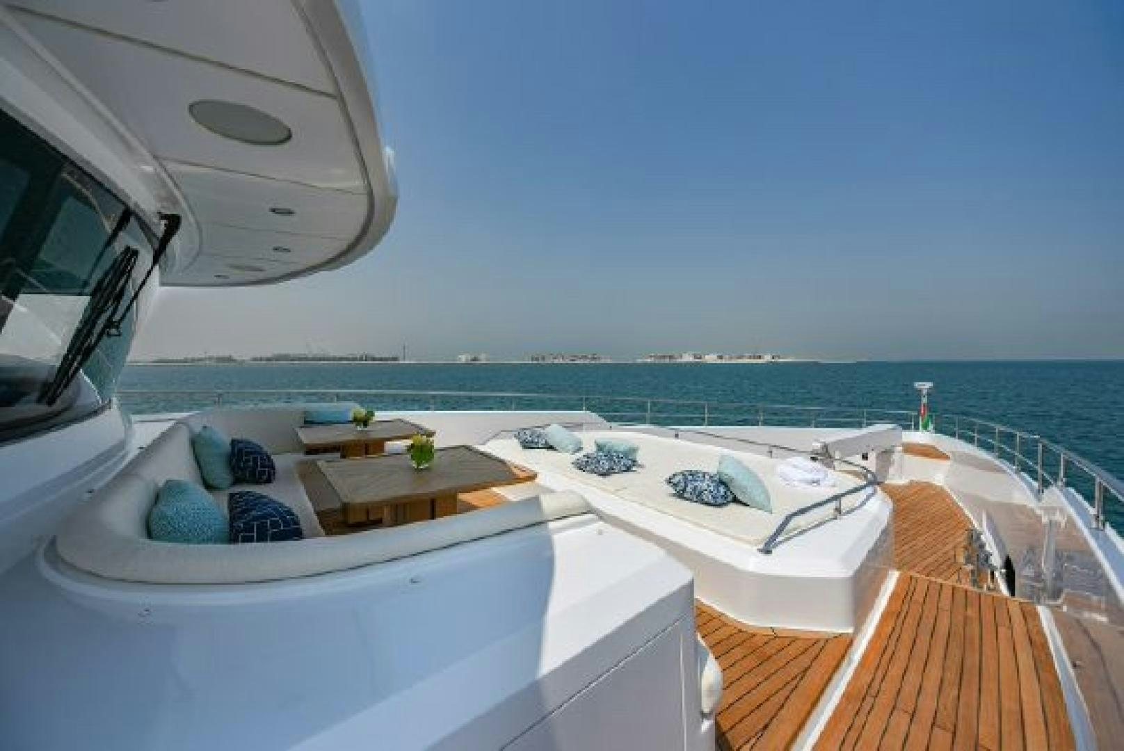 a large white bed on a balcony overlooking a beach aboard No Name Yacht for Sale