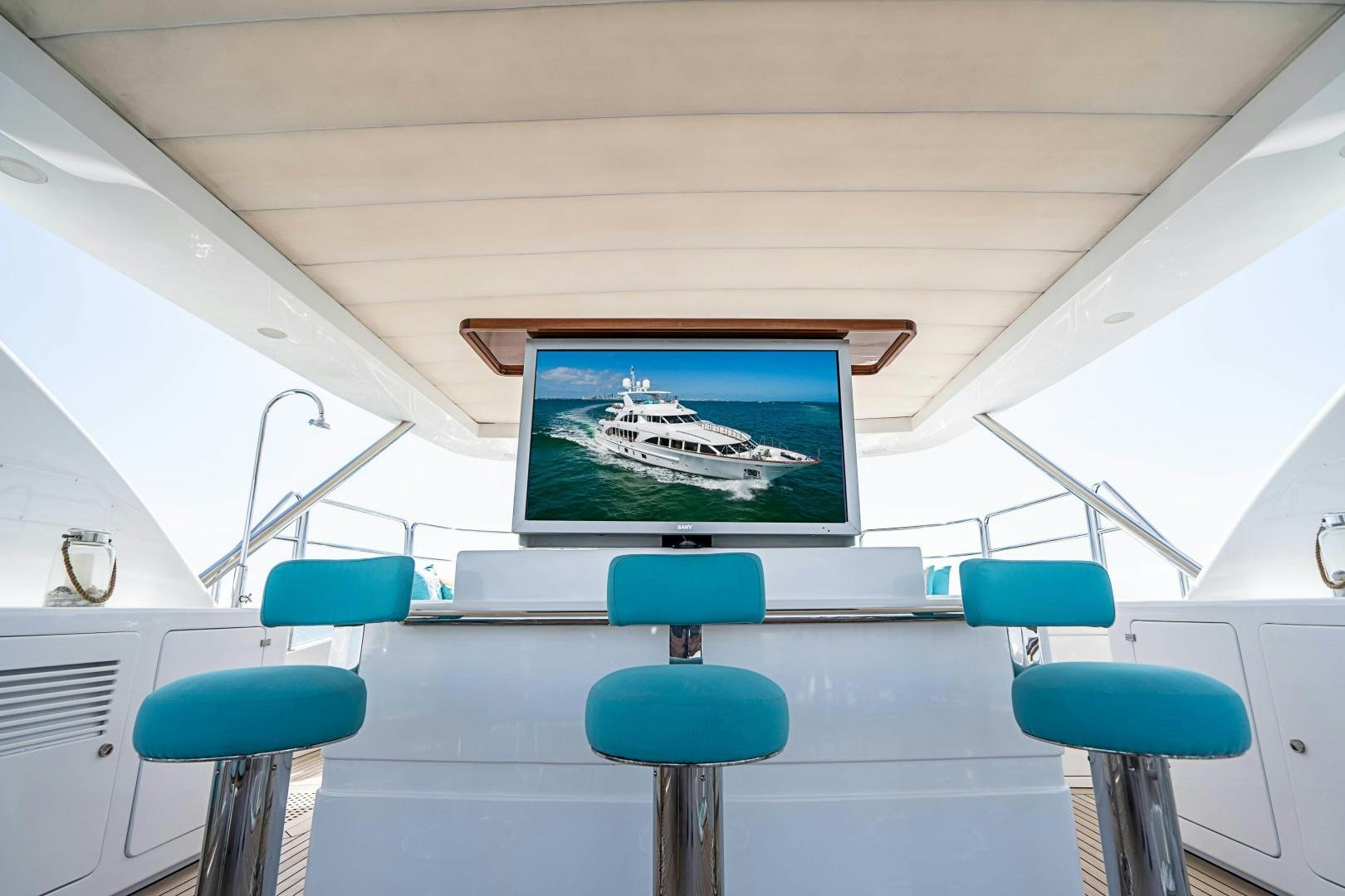 a room with a tv and blue chairs aboard No Name Yacht for Sale