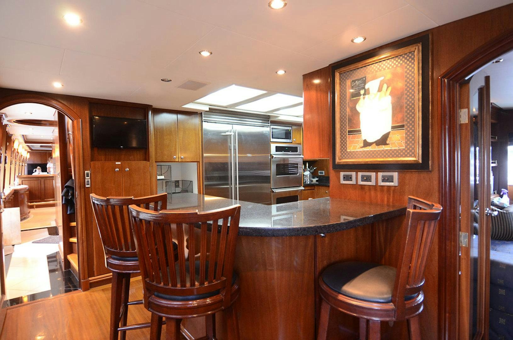 a kitchen with a bar and chairs aboard OCEAN CLUB Yacht for Sale
