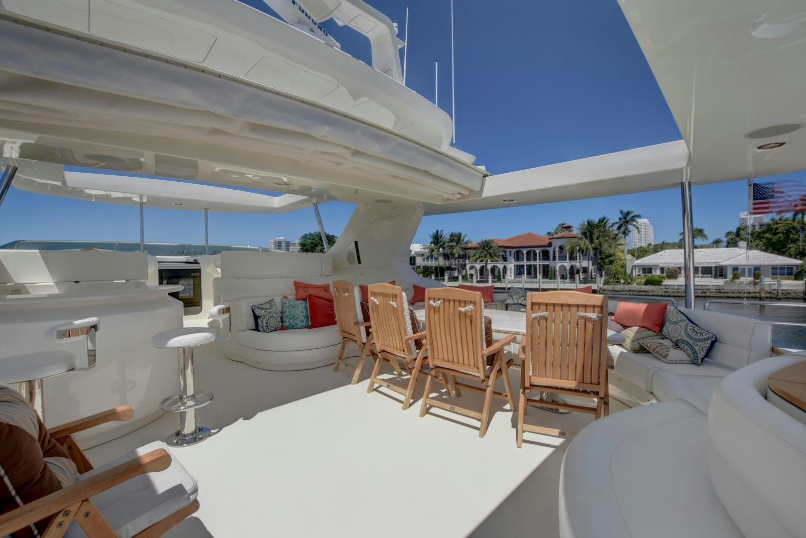 a room with a large white table and chairs and a large white building with blue sky and palm aboard SIN OR SWIM Yacht for Sale