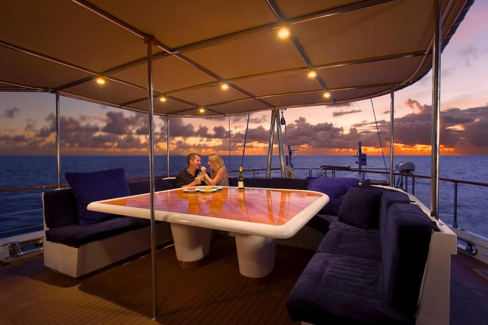 a couple sitting at a table on a boat aboard QUEEN SOUTH III Yacht for Sale