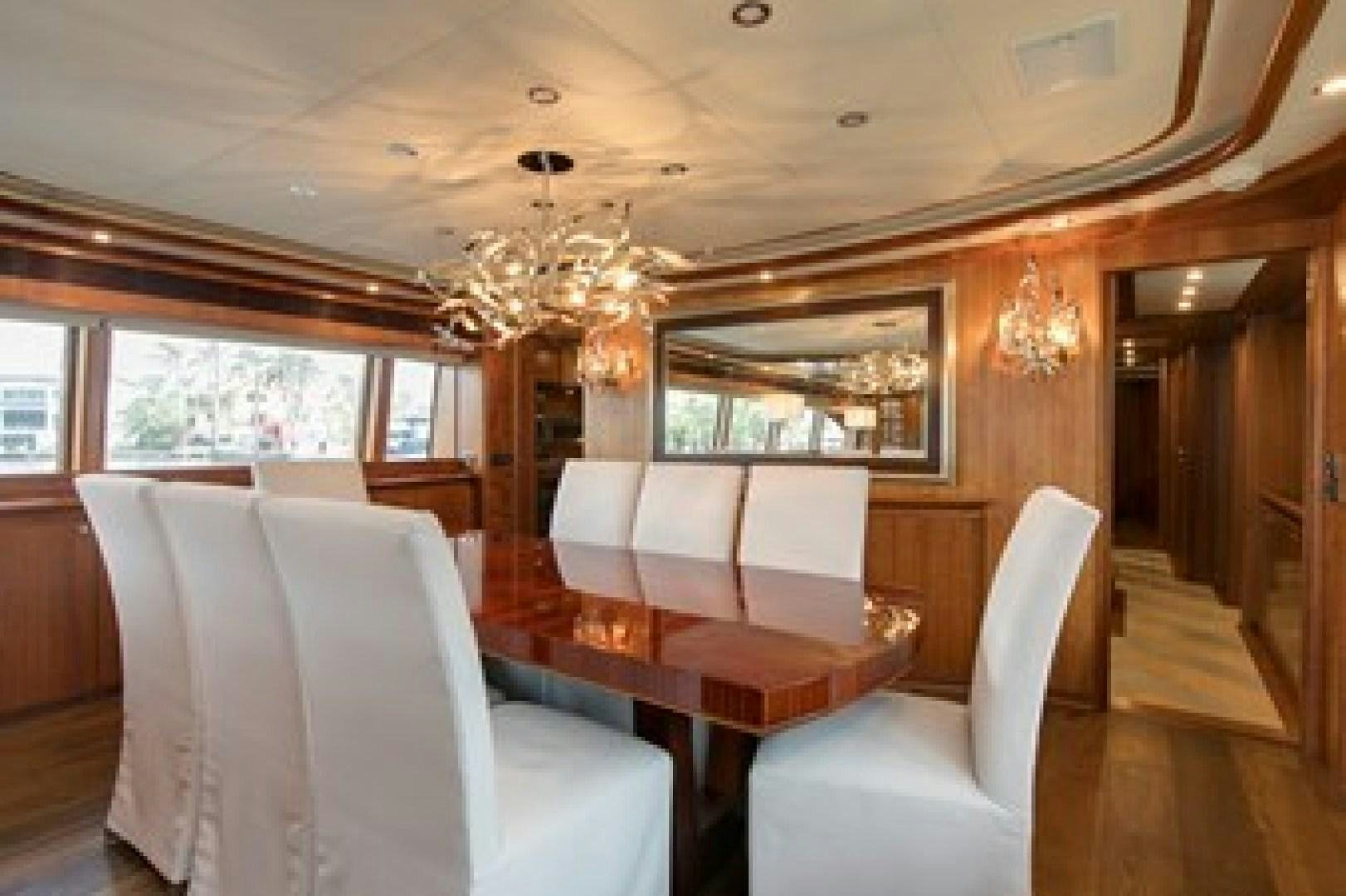 a room with a table chairs and a chandelier aboard MAMBO Yacht for Sale