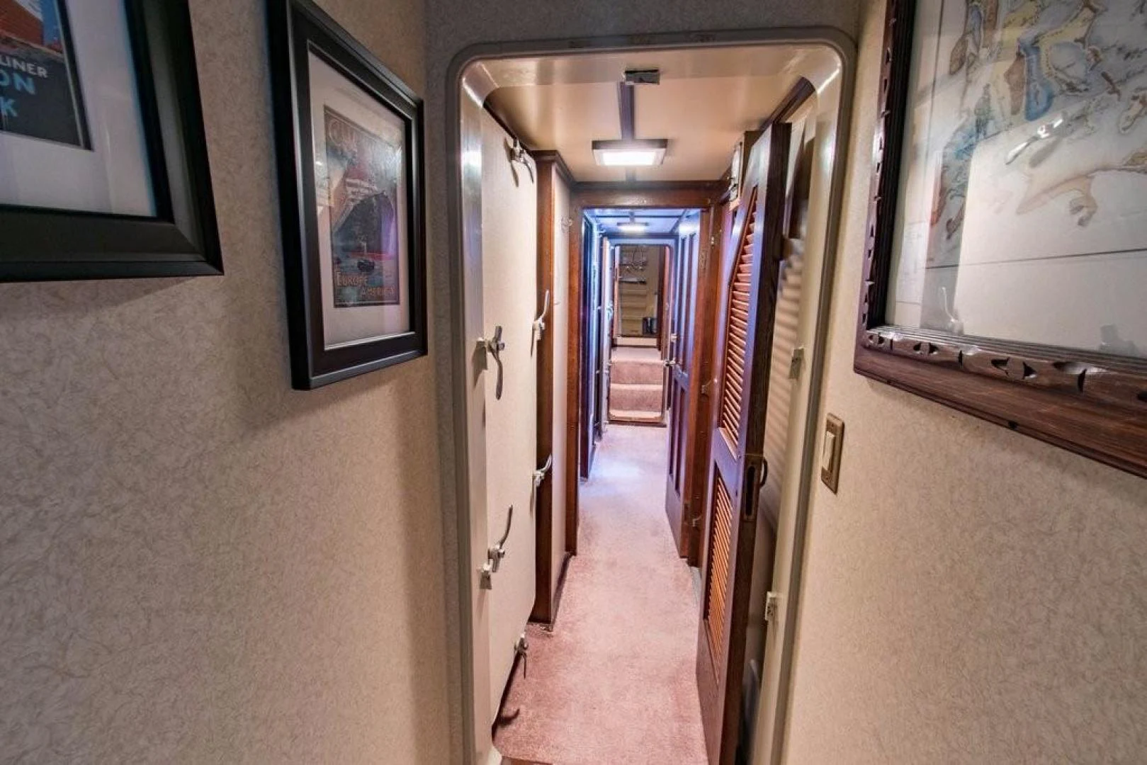 a hallway with a door and pictures on the wall aboard TIMELESS Yacht for Sale