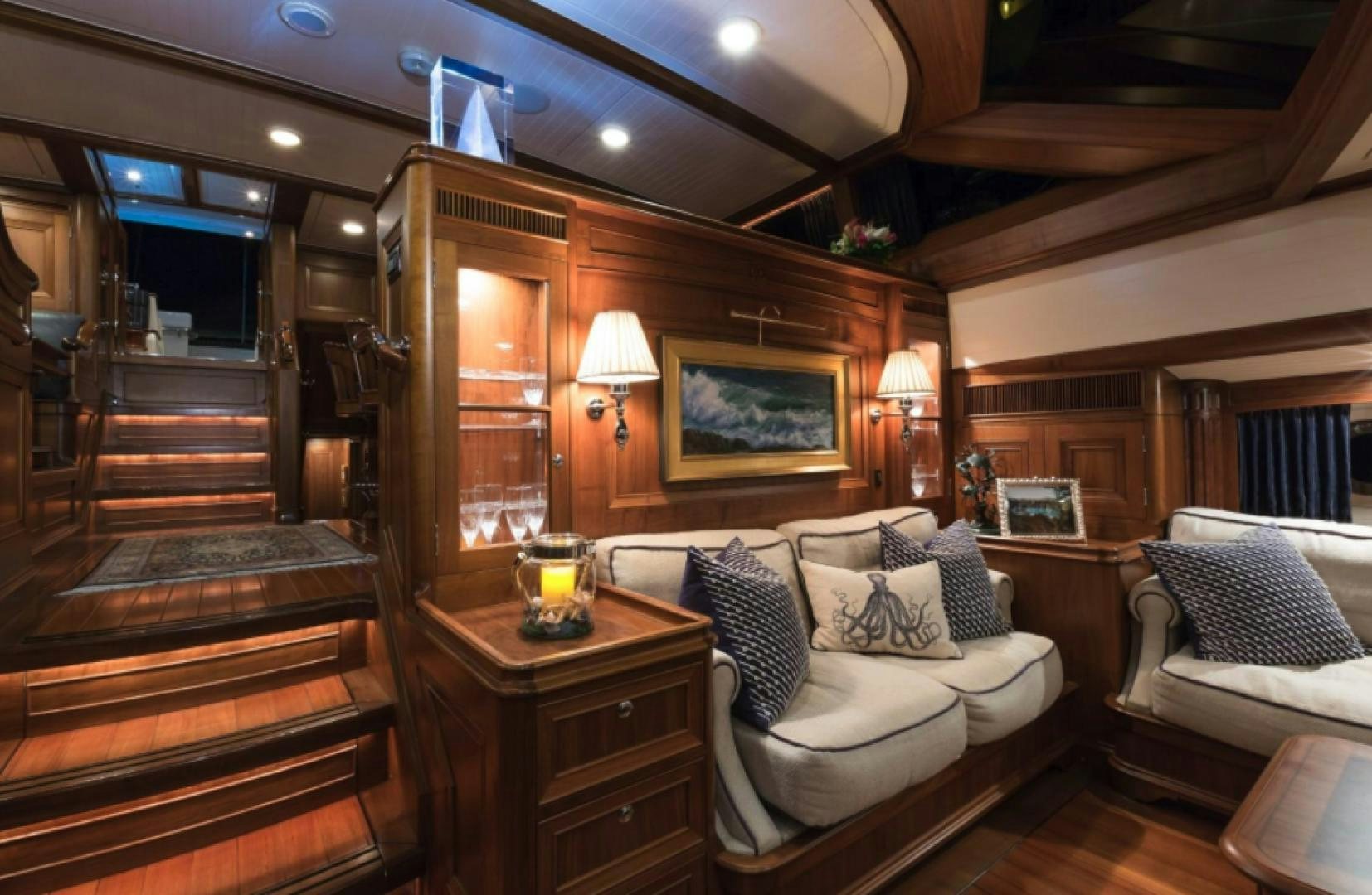 a room with a bed and a table with a lamp on it aboard MARAE Yacht for Sale