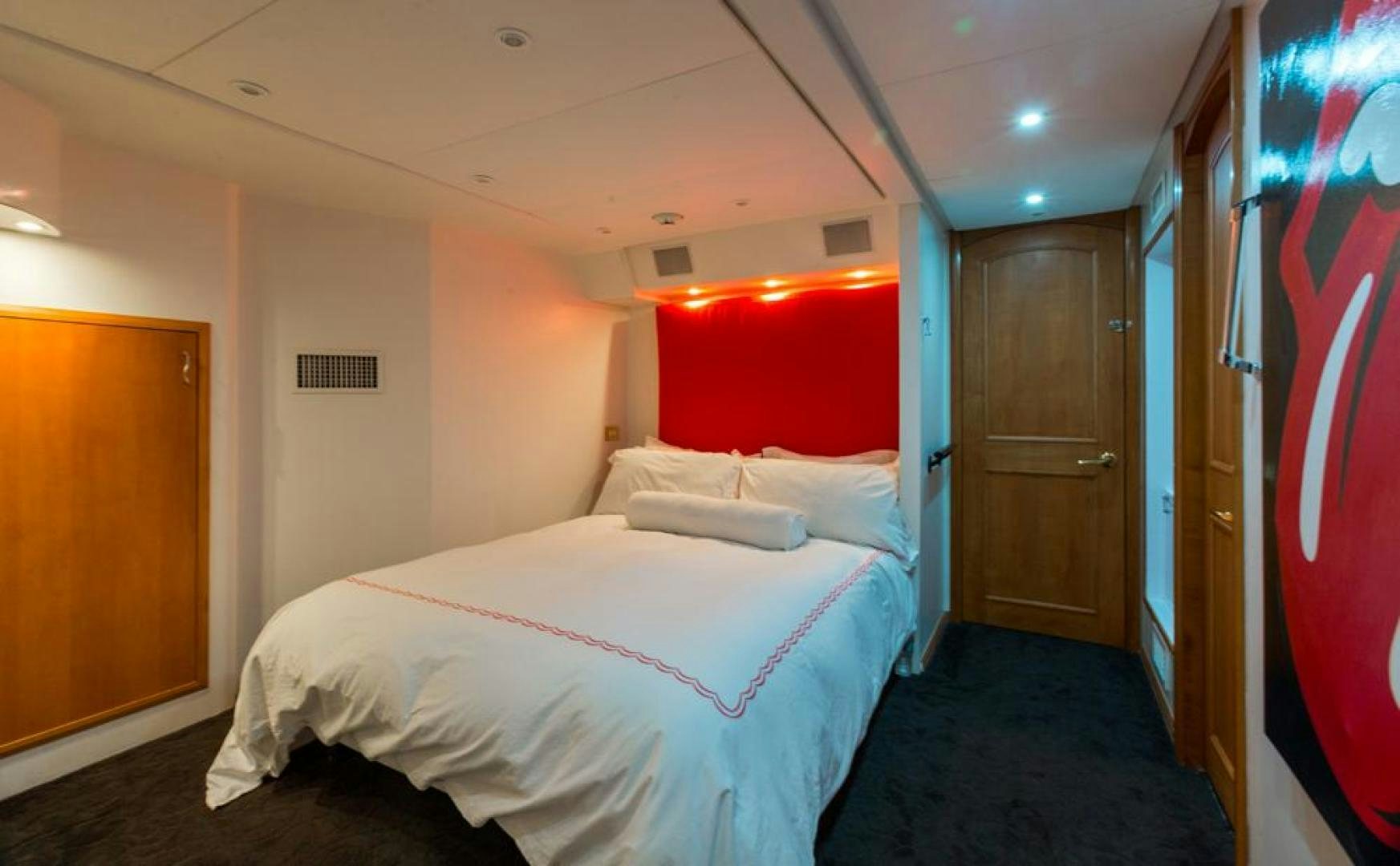 a room with a bed and a red wall aboard PIRATE RADIO Yacht for Sale
