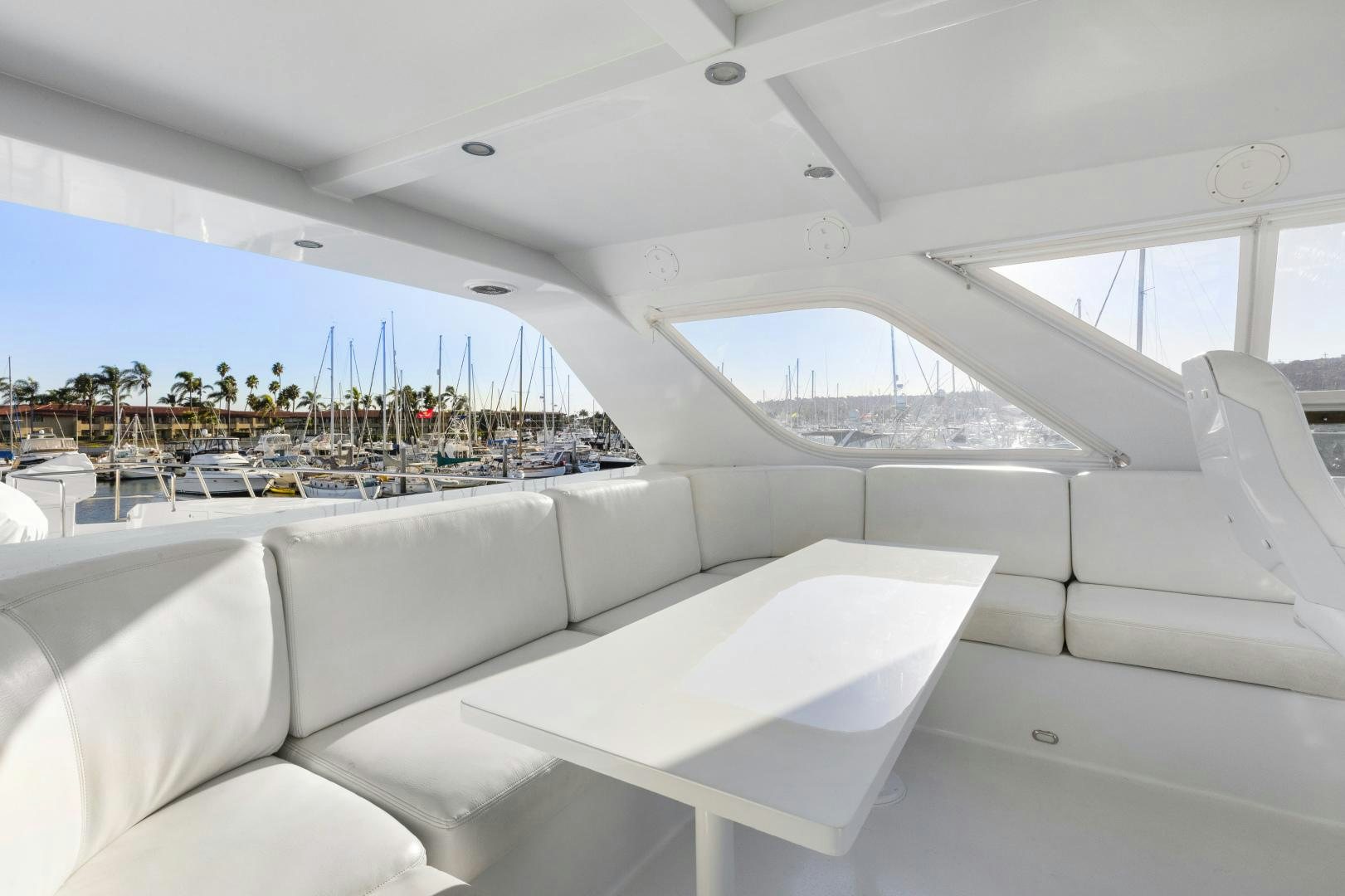 a white lounge chair in a room with a large white window and a view of a city and aboard ILLEAGLE Yacht for Sale