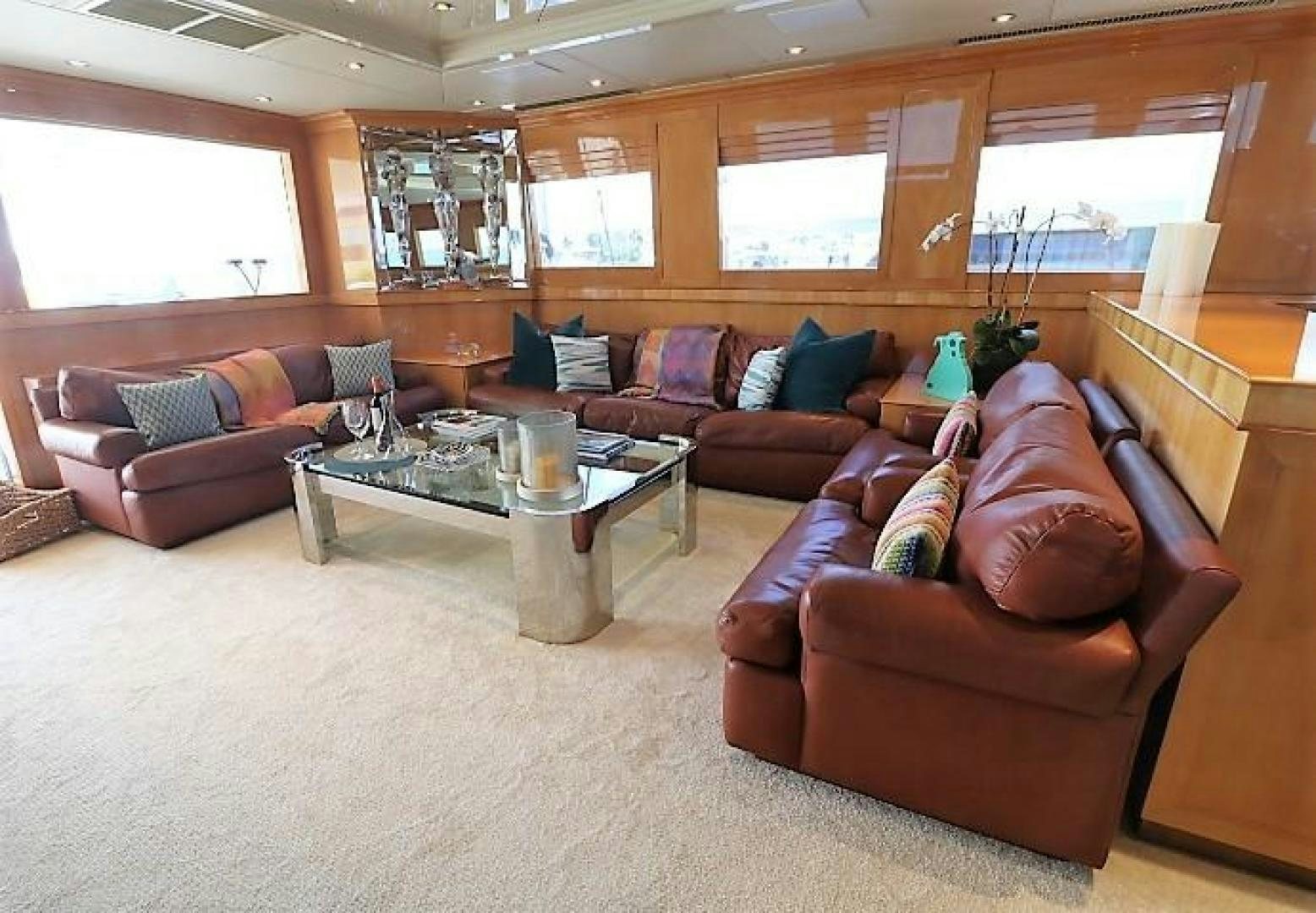 a living room with brown leather couches and a coffee table aboard No Name Yacht for Sale