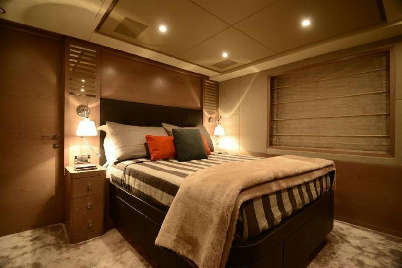 a bed with a white comforter and pillows in a room with a window and a wood wall aboard No Name Yacht for Sale