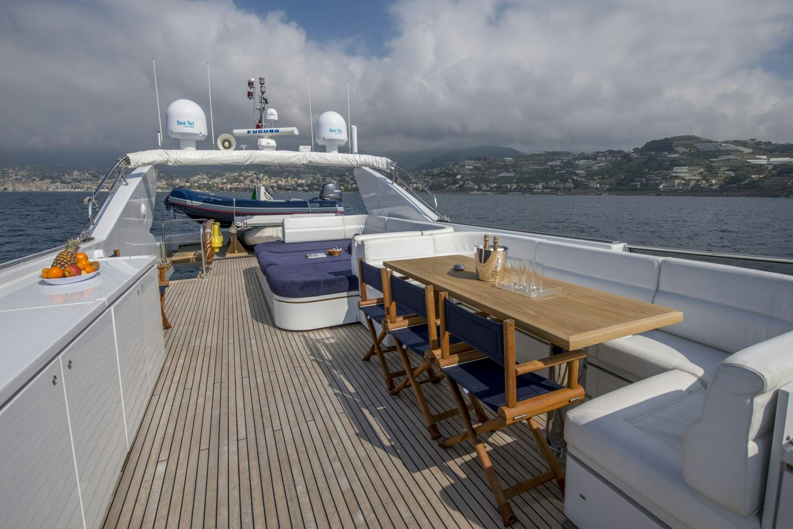 a deck with a table and chairs on it and a boat in the water aboard GIOIA 1 Yacht for Sale