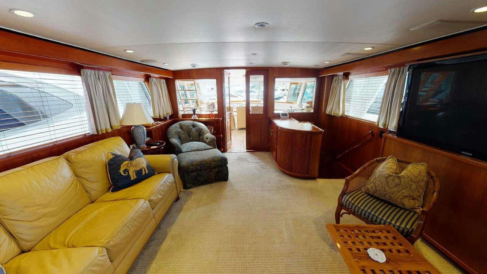 a living room with a yellow couch and a television aboard LORELEI Yacht for Sale