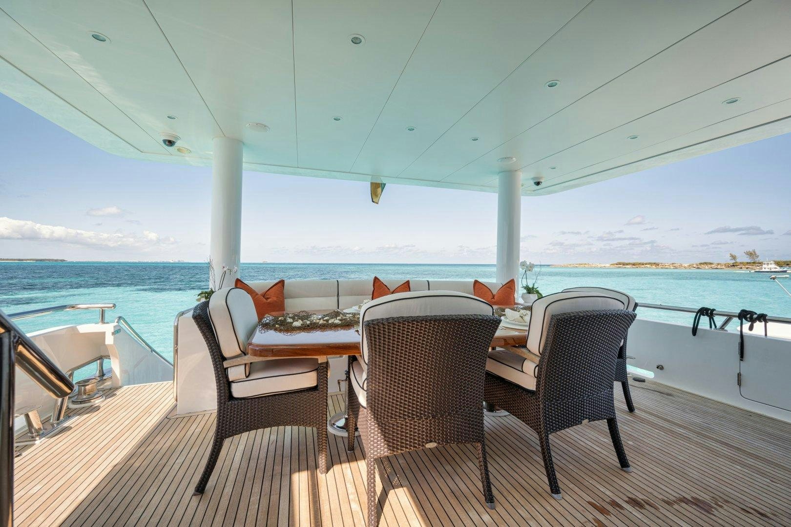 a table and chairs on a deck overlooking the ocean aboard LIMITLESS Yacht for Sale
