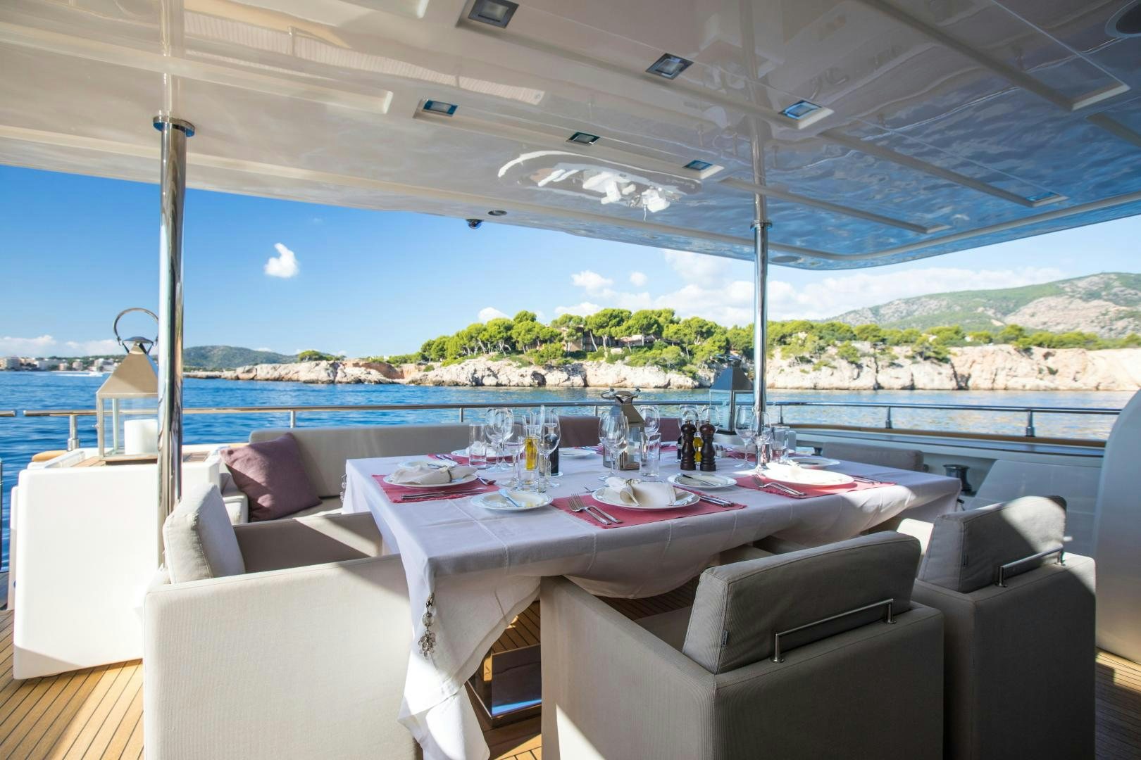 a table set for a meal on a deck overlooking a large body of water aboard CAMPO VERDE Yacht for Sale