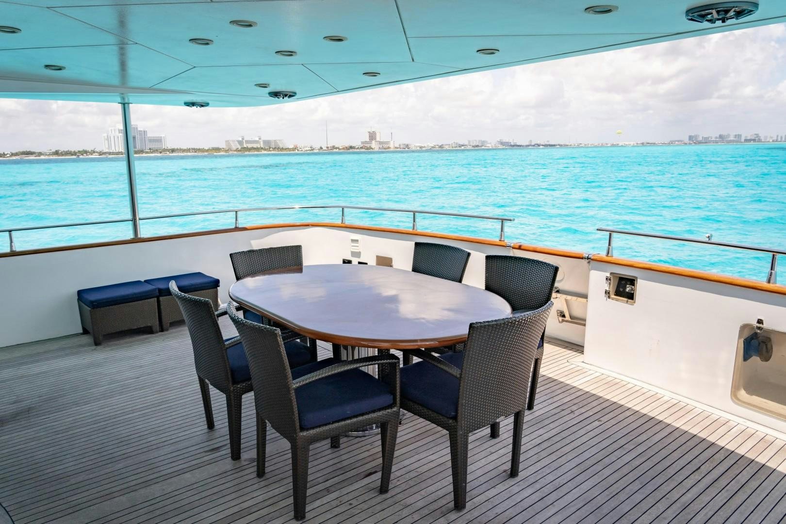 a table and chairs on a deck overlooking a body of water aboard EL CAPRICHO Yacht for Sale