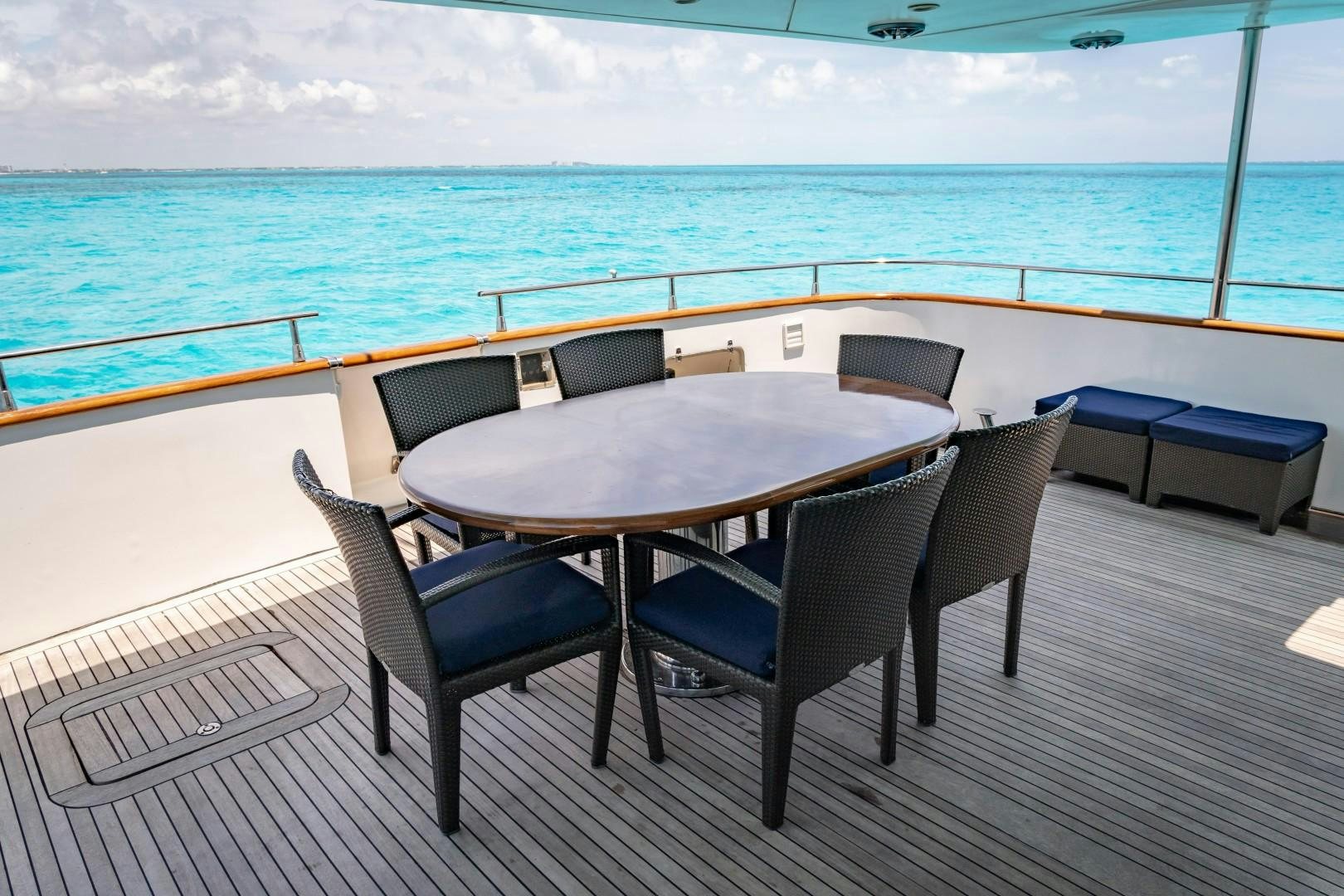 a table and chairs on a deck overlooking a body of water aboard EL CAPRICHO Yacht for Sale