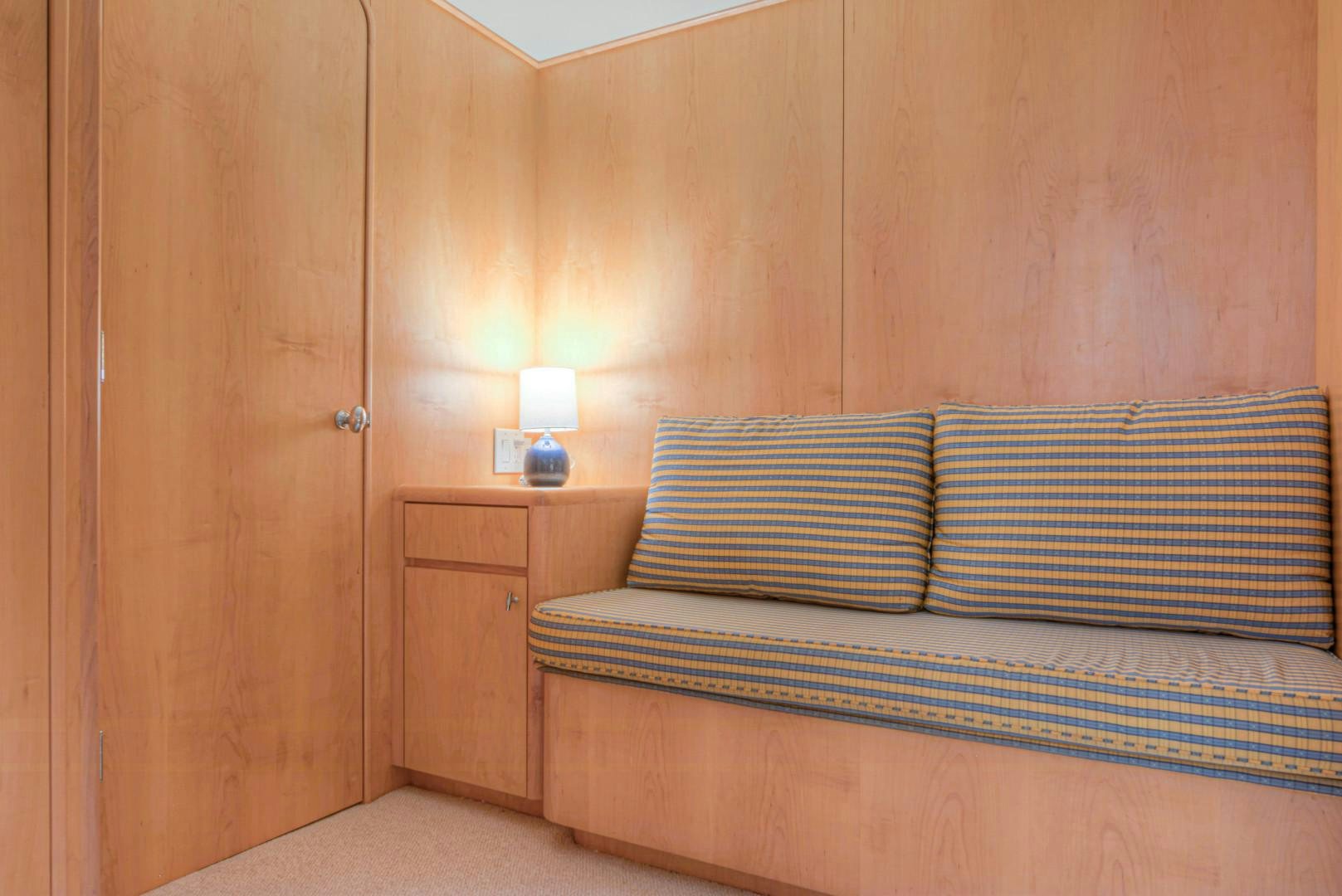 a bed with a blue and yellow striped pillow and a wooden wall aboard LADY LEX Yacht for Sale