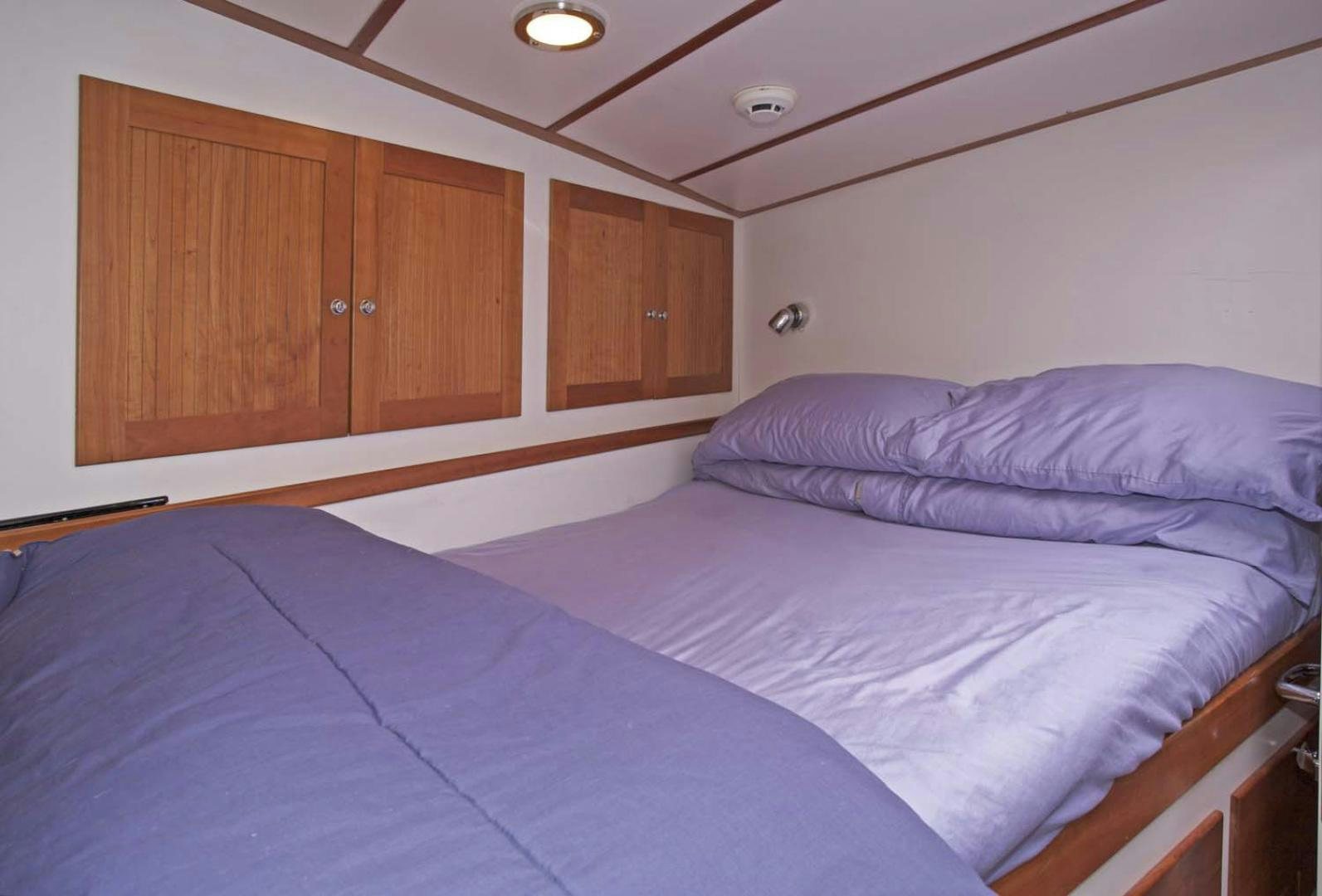 a bedroom with a bed and cabinets aboard BRAVO Yacht for Sale