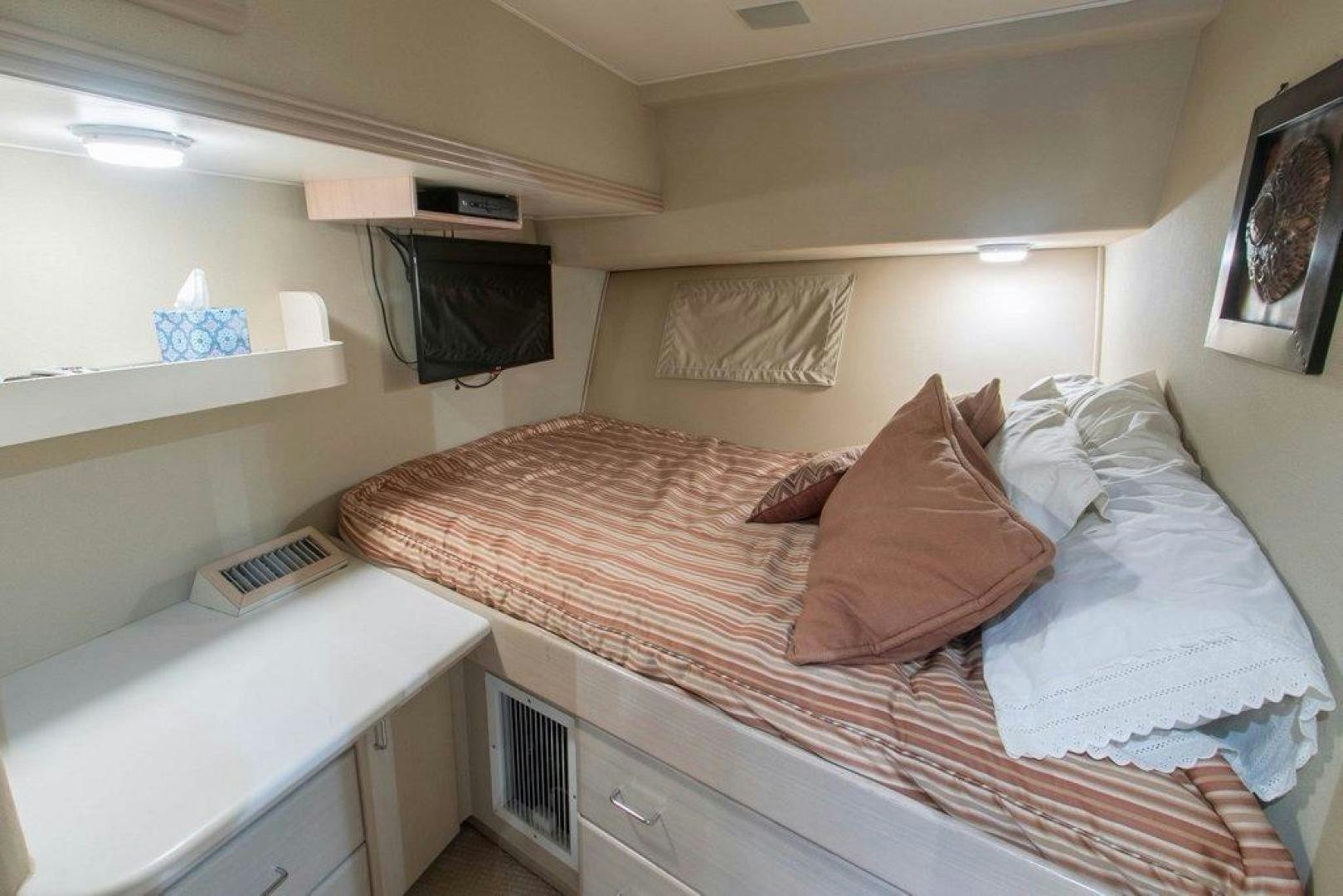 a bed with a television on the wall aboard MONARCH Yacht for Sale