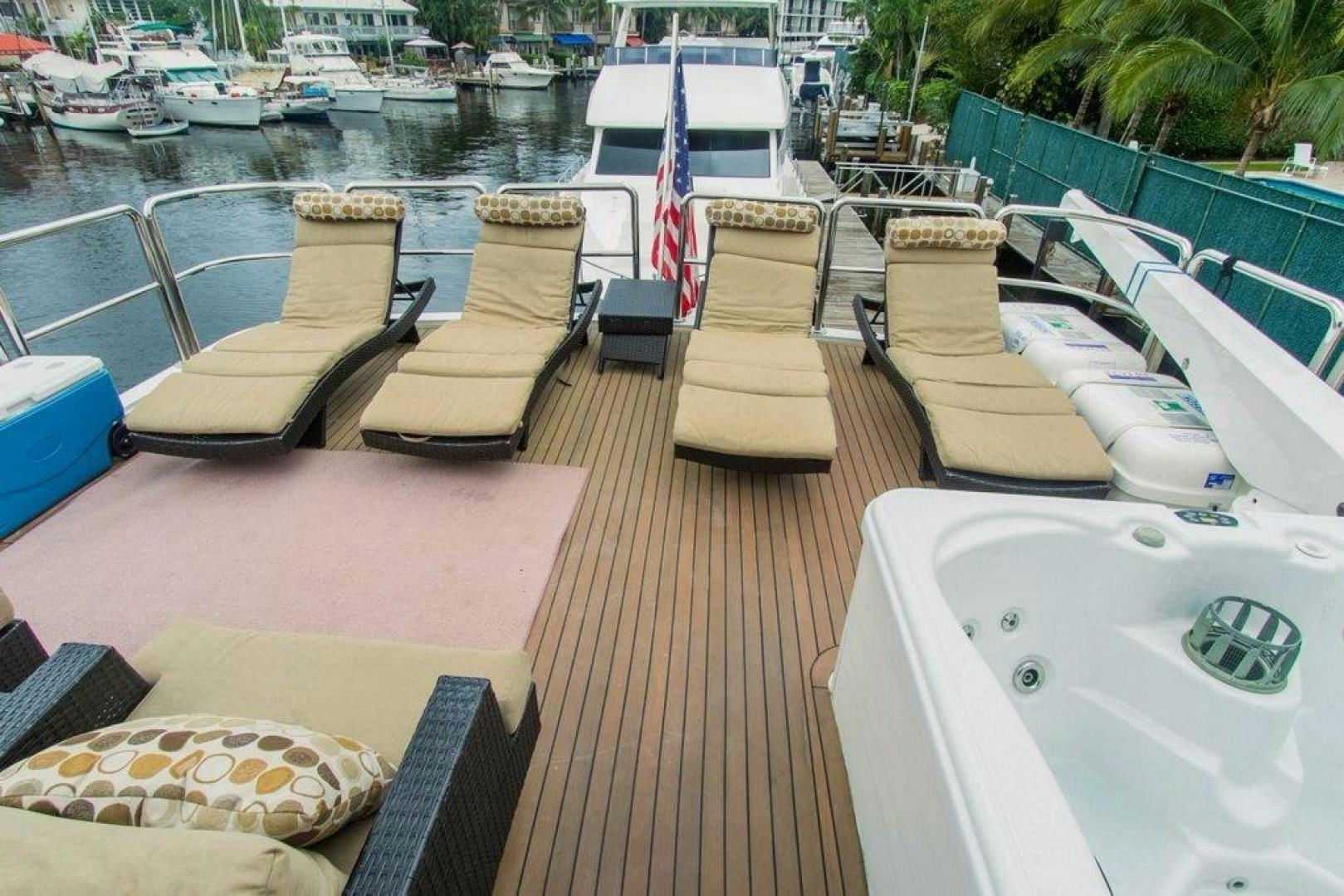 a deck with chairs and a table with boats in the water aboard MONARCH Yacht for Sale