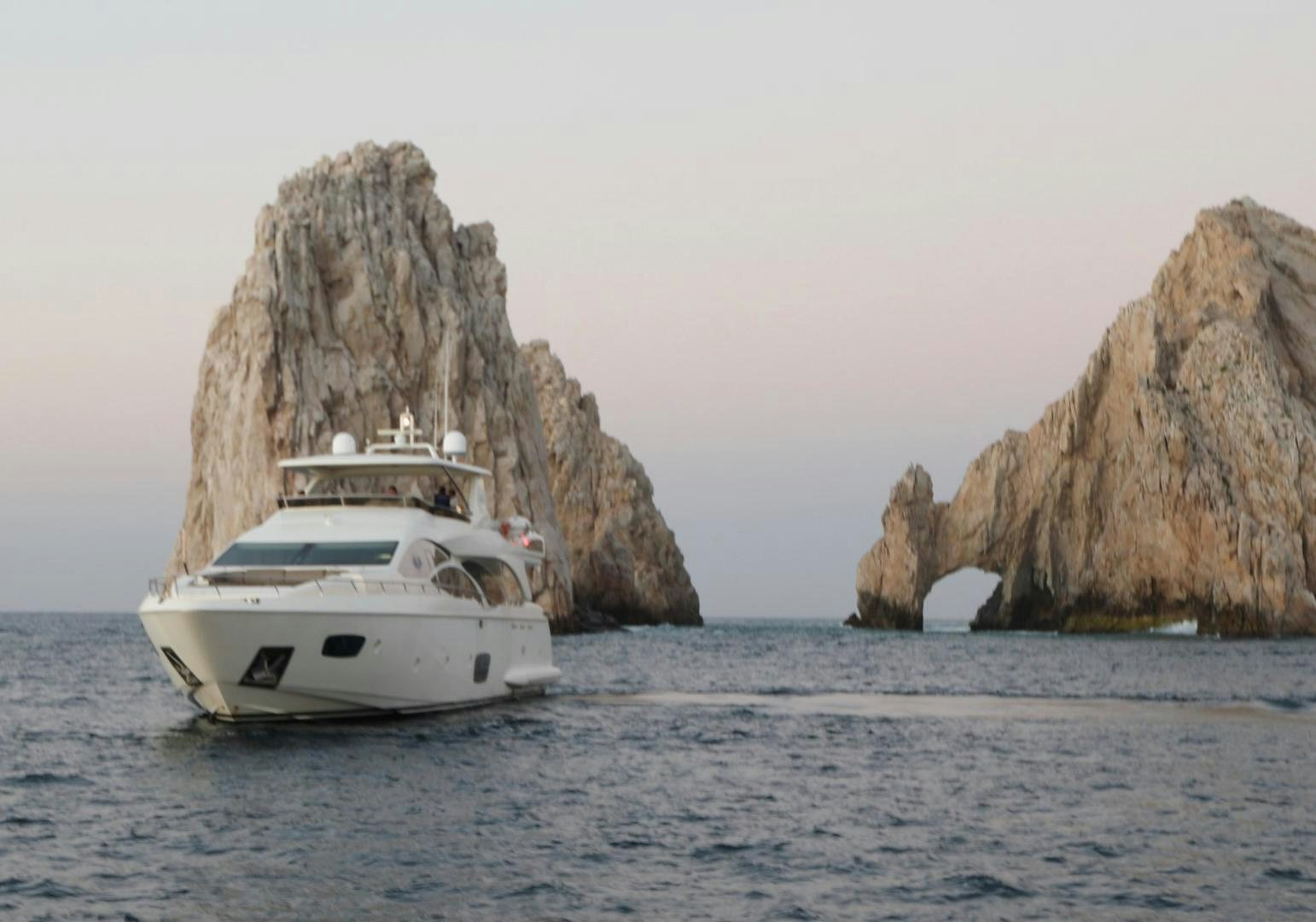 a boat in the water with Arch of Cabo San Lucas in the background aboard ANDREIKA Yacht for Sale