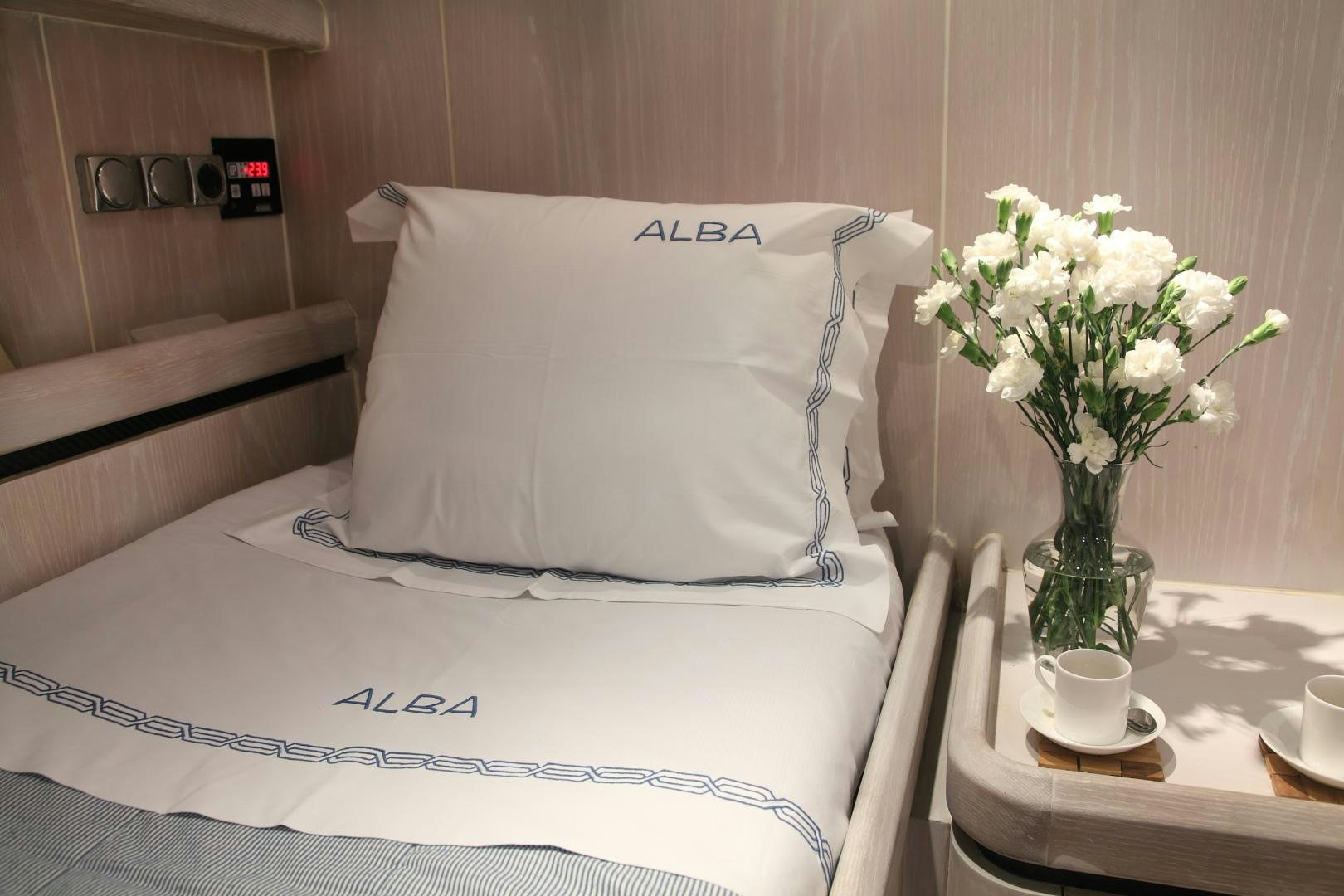 a bed with white pillows and white flowers in a room aboard MARIA ALBA Yacht for Sale