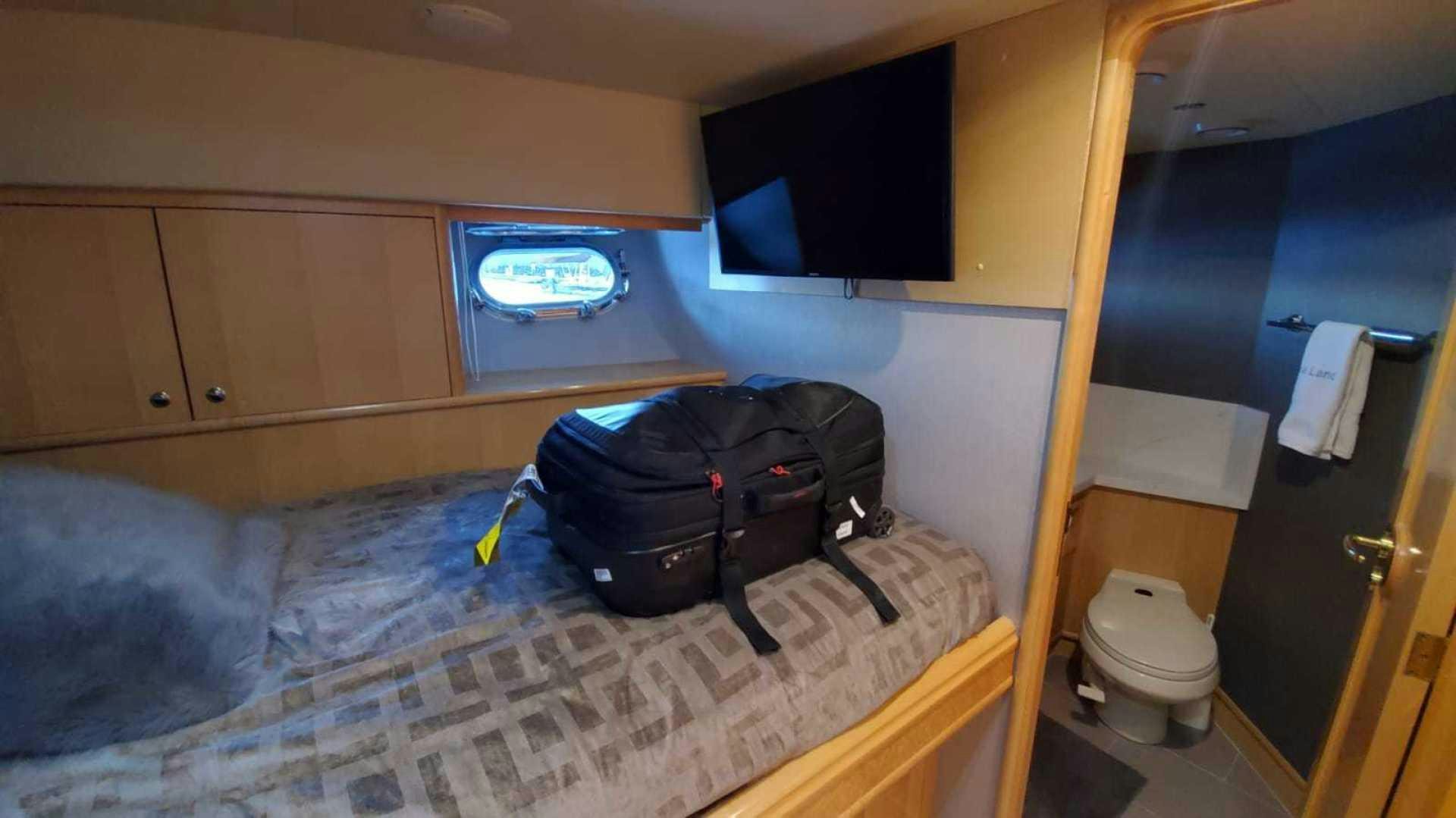 a small room with a bed and a television aboard LA LA LAND Yacht for Sale