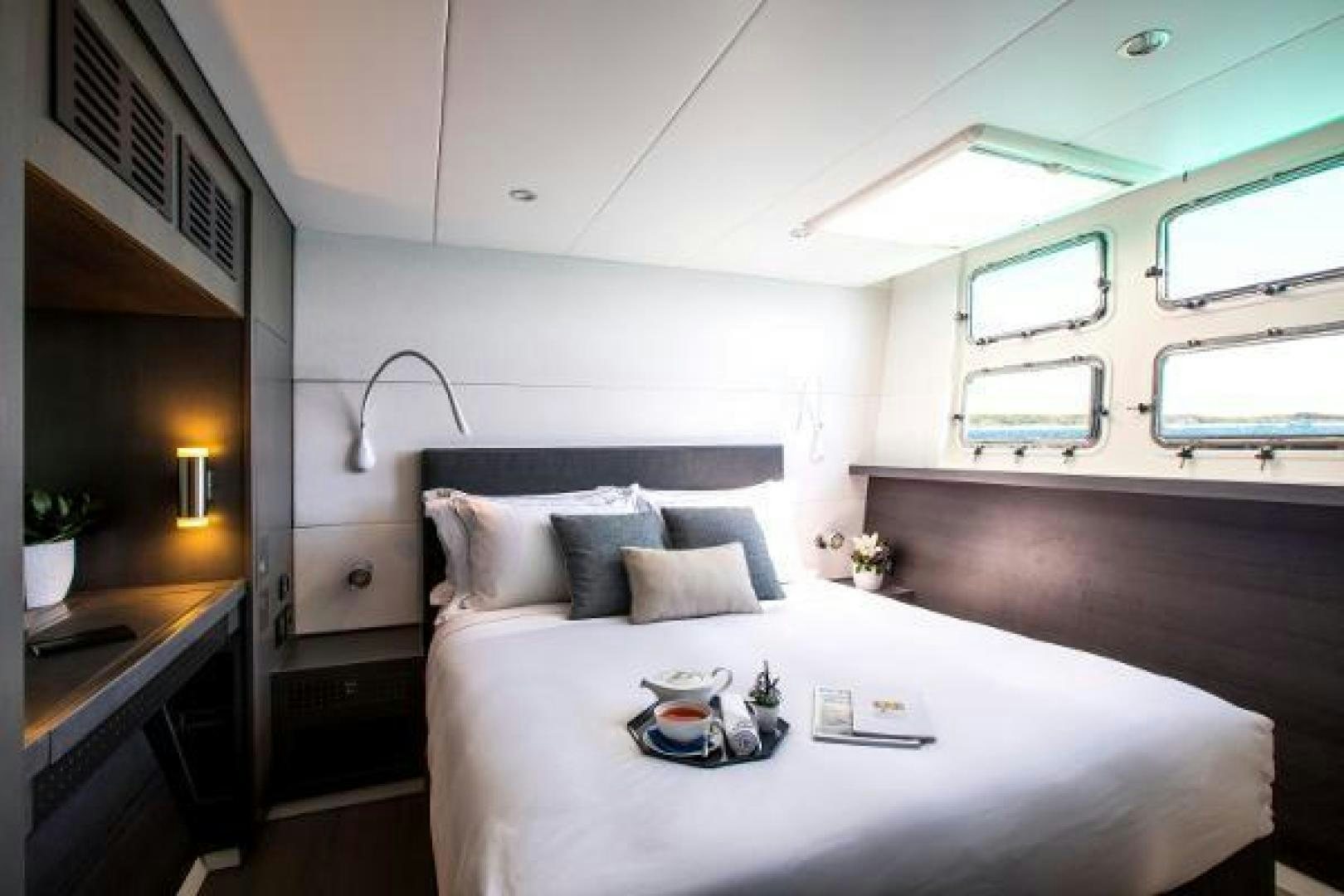 a room with a bed and a table aboard CARTOUCHE Yacht for Sale