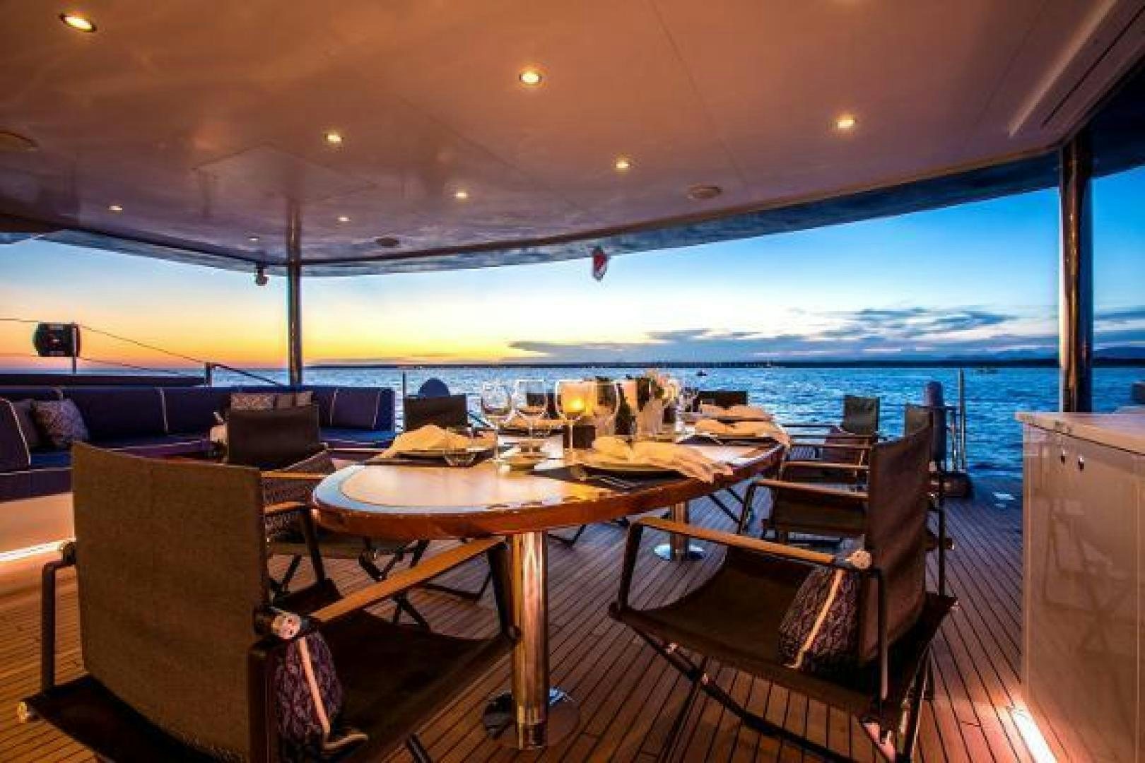 a table set for a meal on a deck overlooking the ocean aboard CARTOUCHE Yacht for Sale